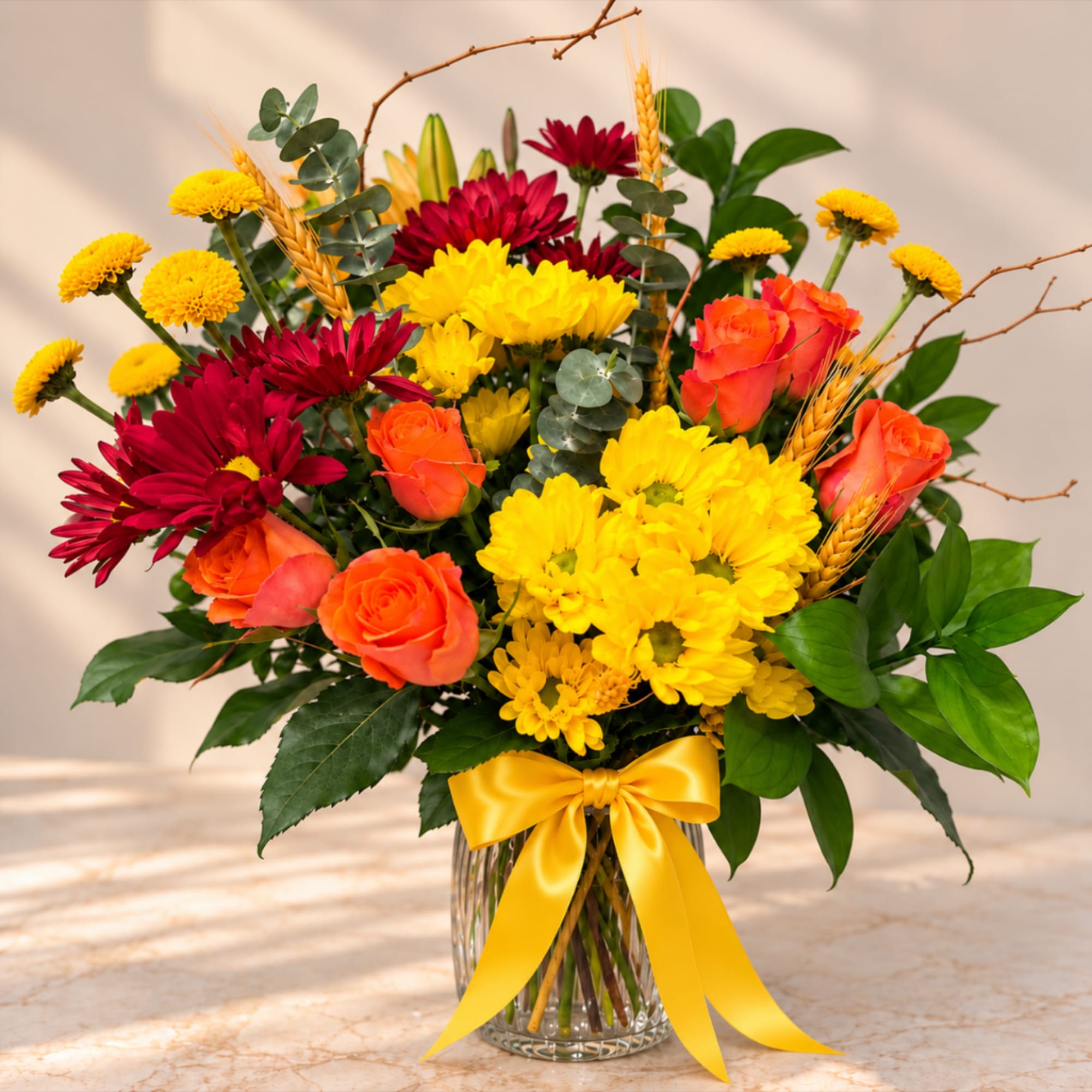 Bouquet of yellow and orange flowers in a glass vase with a yellow ribbon
