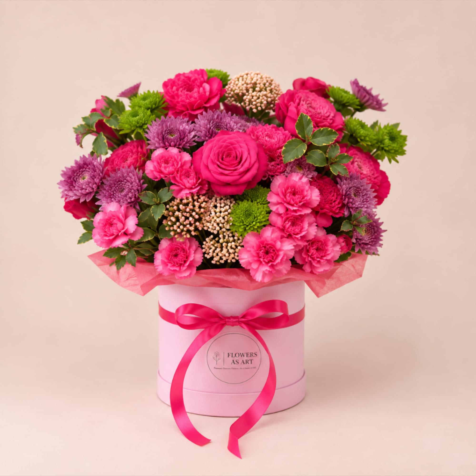 Pink and purple flower arrangement in a round box with a ribbon