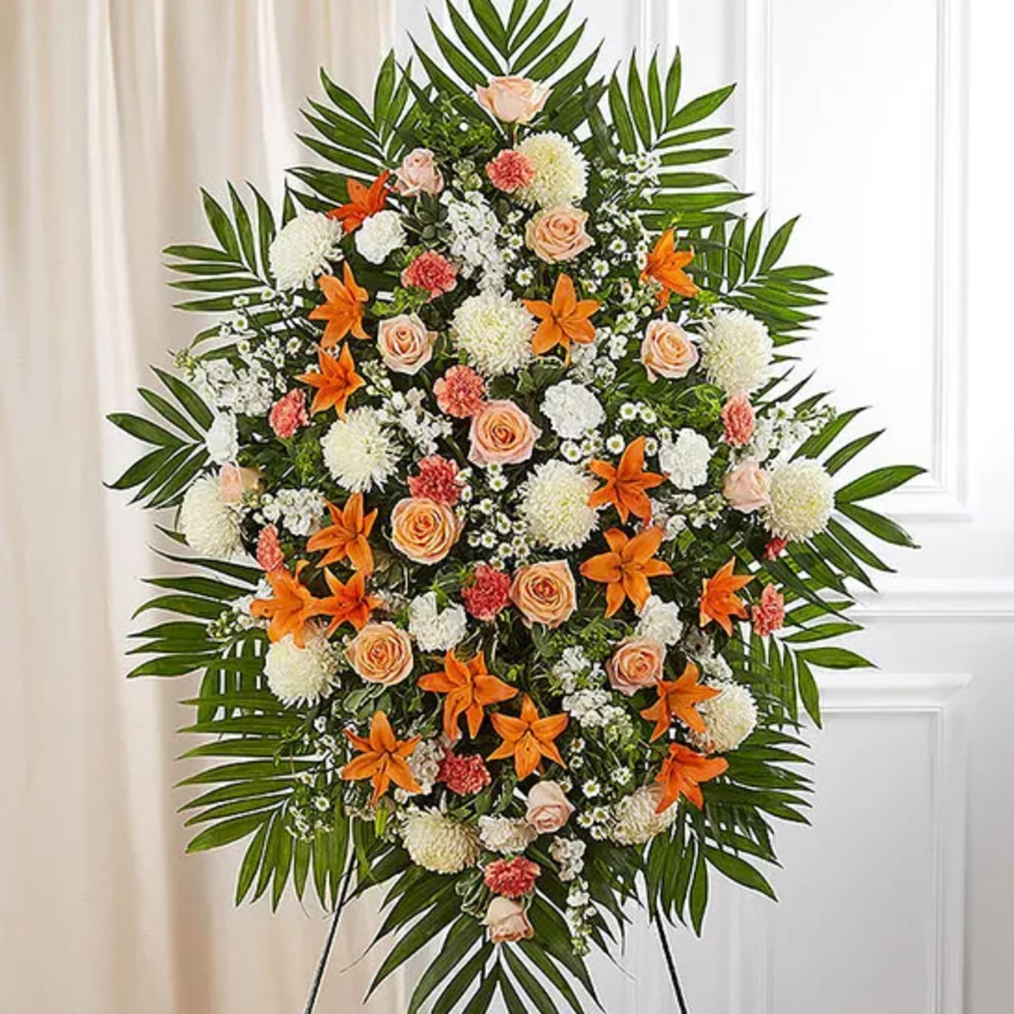 Standing floral spray with orange lilies, peach roses, and white blooms