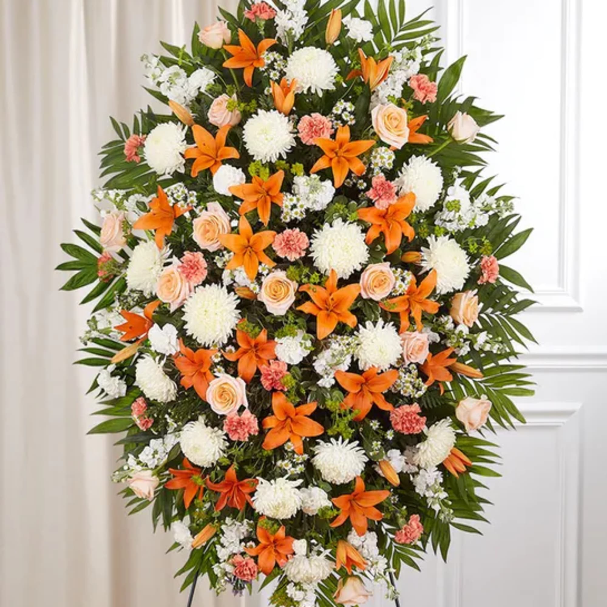 Standing floral spray with orange lilies, white mums, and pale roses