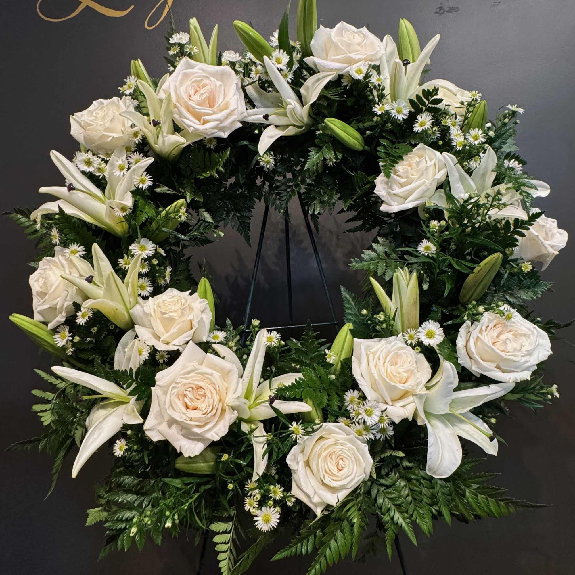 A simple and elegant sympathy wreath designed with fresh white blooms and