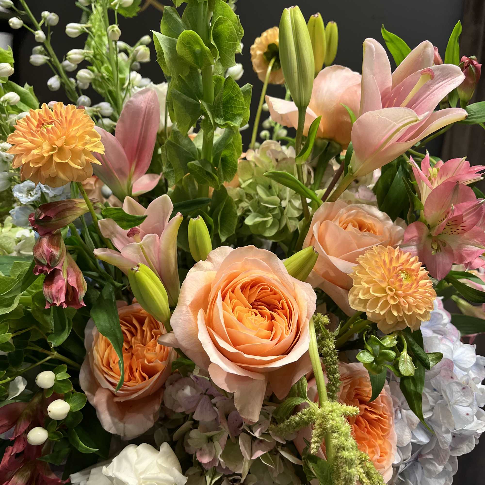 Mixed bouquet with peach roses, pink lilies, and orange blooms