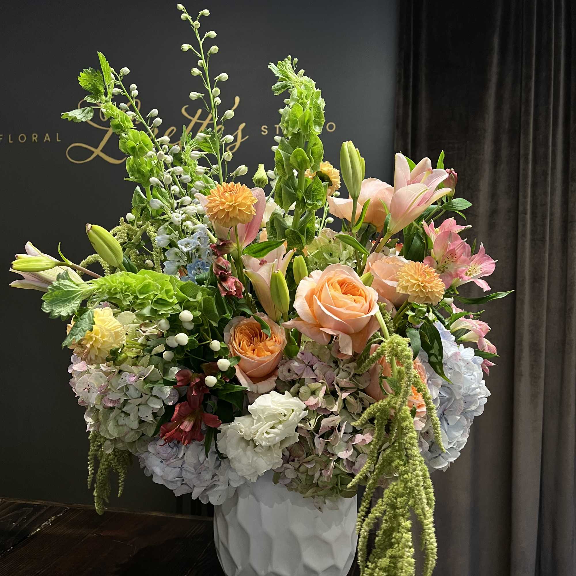 Large pastel floral arrangement in a white textured vase