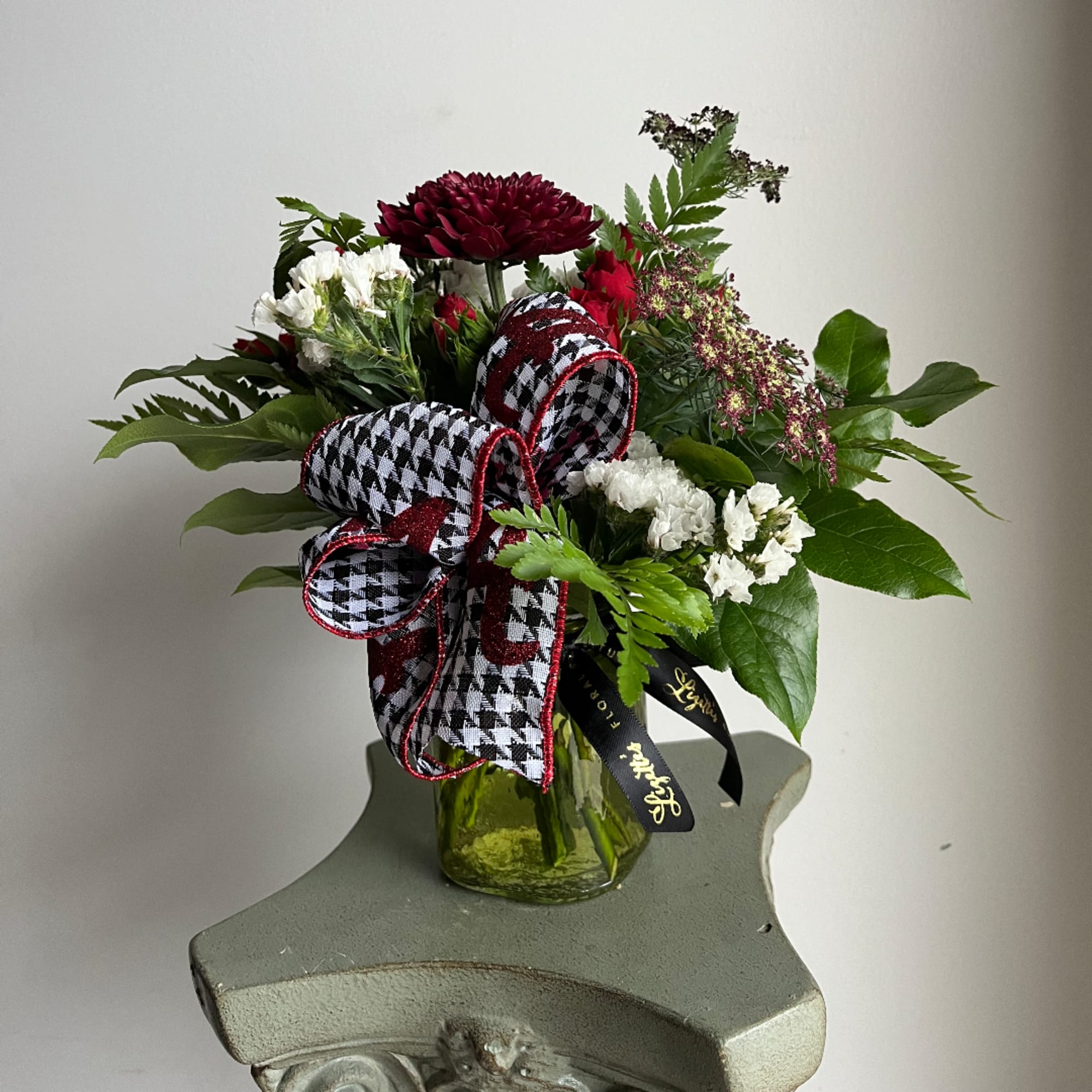 Bouquet of red and white flowers in a glass vase with a plaid ribbon