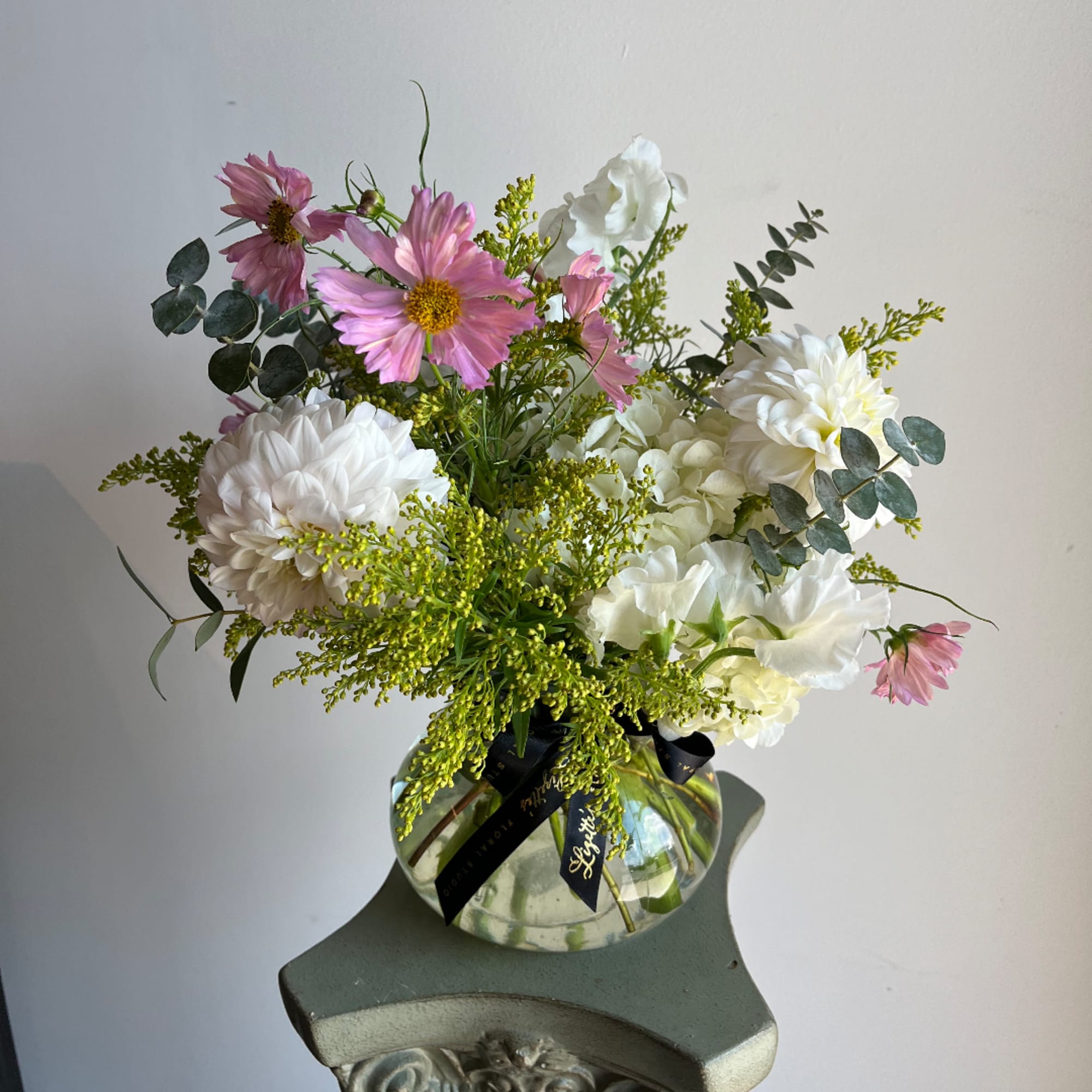 Pink and white flower arrangement in a round glass vase