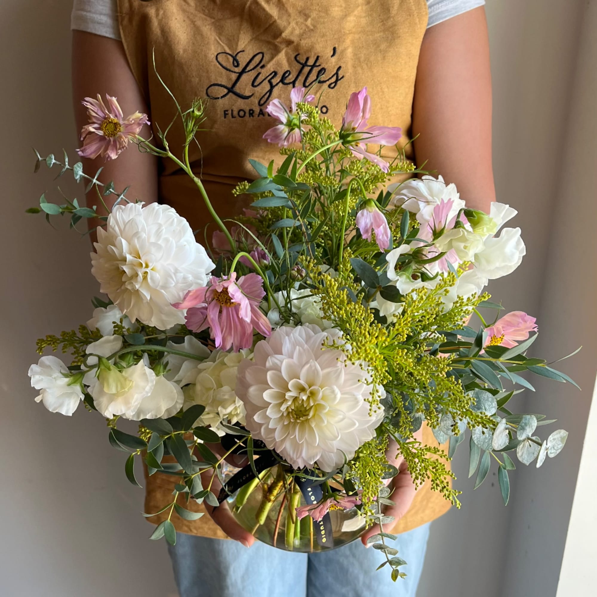 Handheld bouquet of white dahlias and pink cosmos in a glass vase