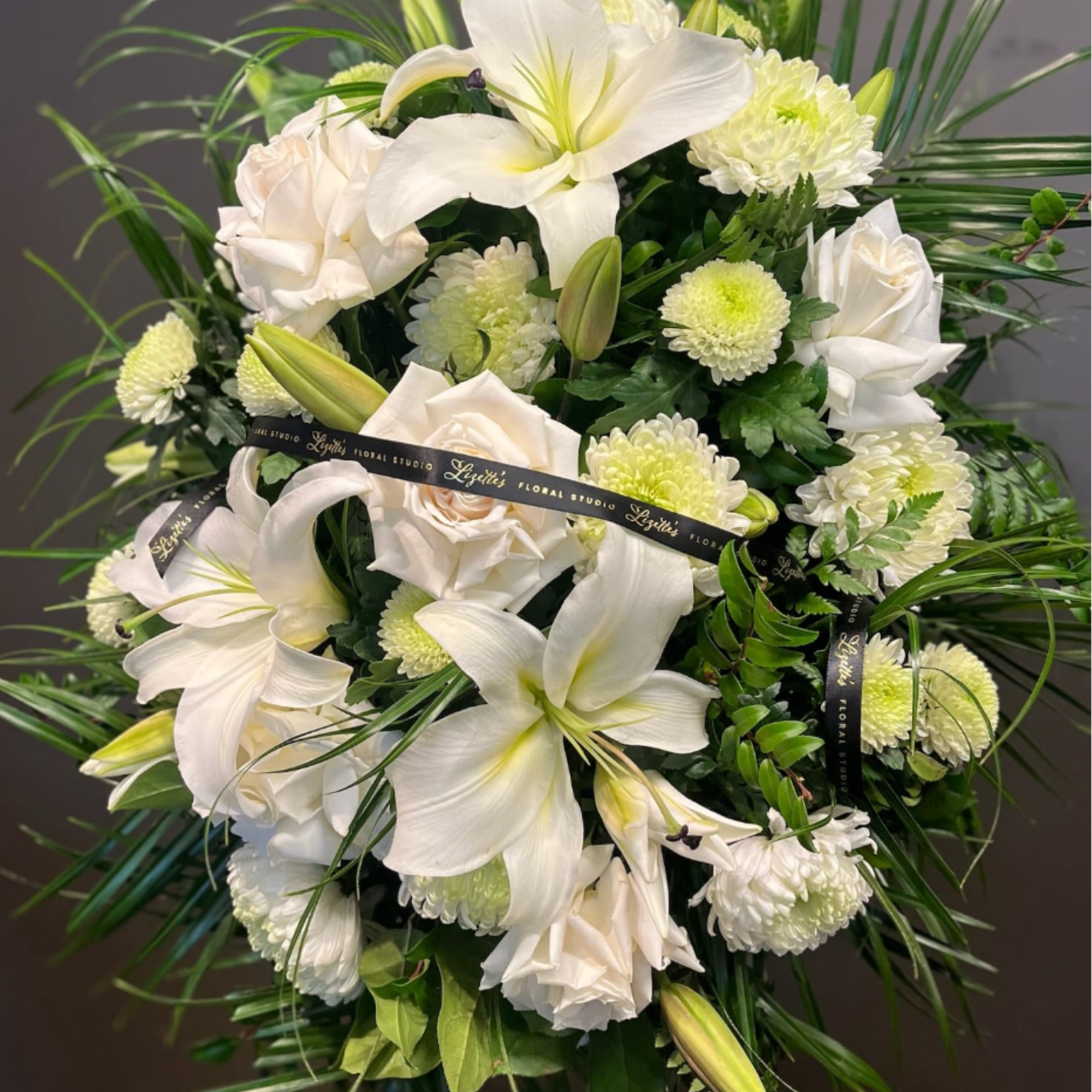 White lilies and roses with pale green mums in a floral spray