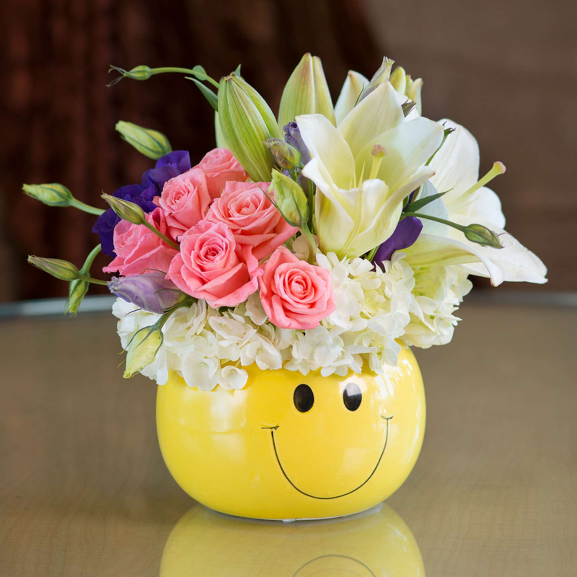 Pink roses and white lilies in a yellow smiley-face vase
