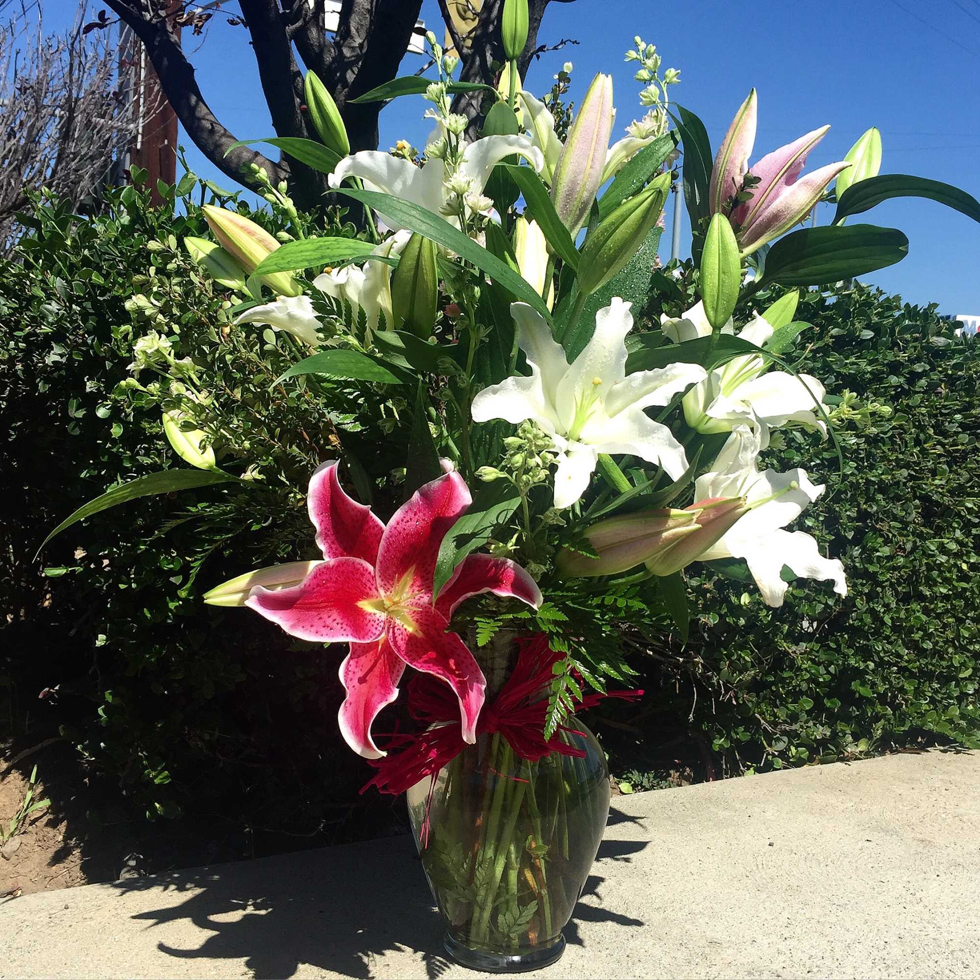 Tall bouquet of lilies in a clear glass vase with pink, white, and green blooms