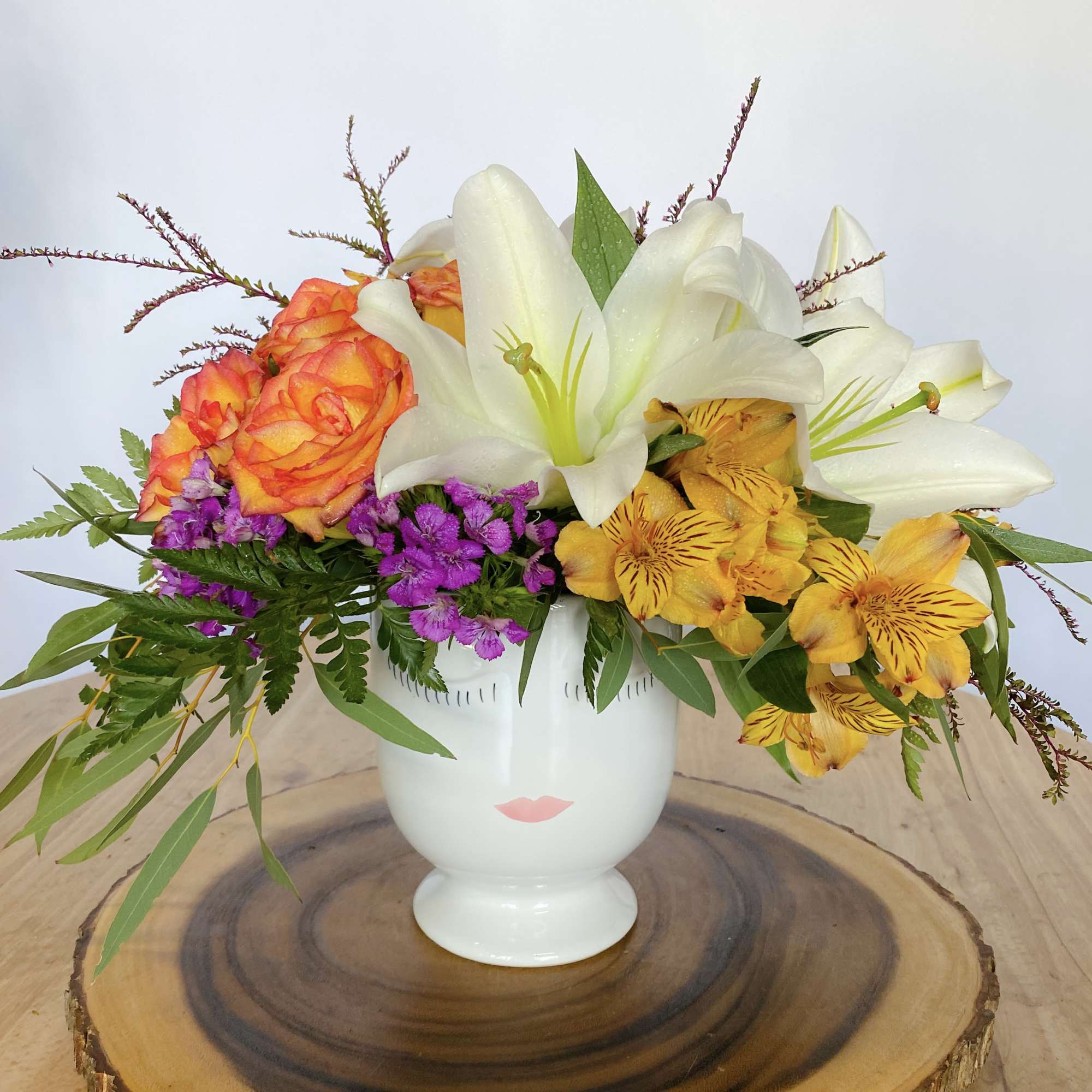Colorful flower arrangement in a white vase with lilies and roses