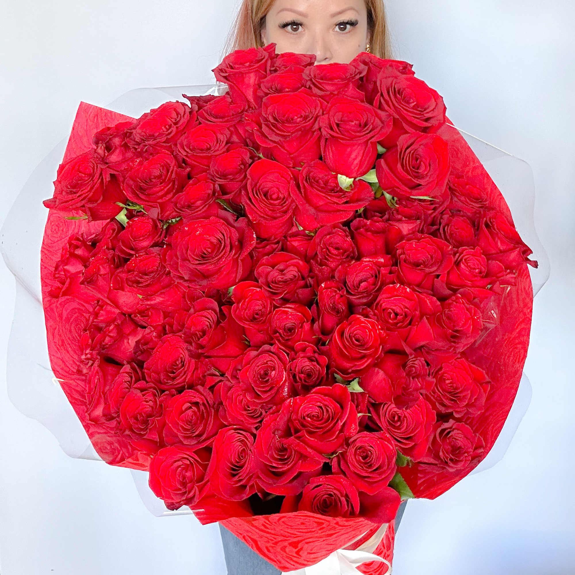 Large bouquet of red roses wrapped in red and clear paper