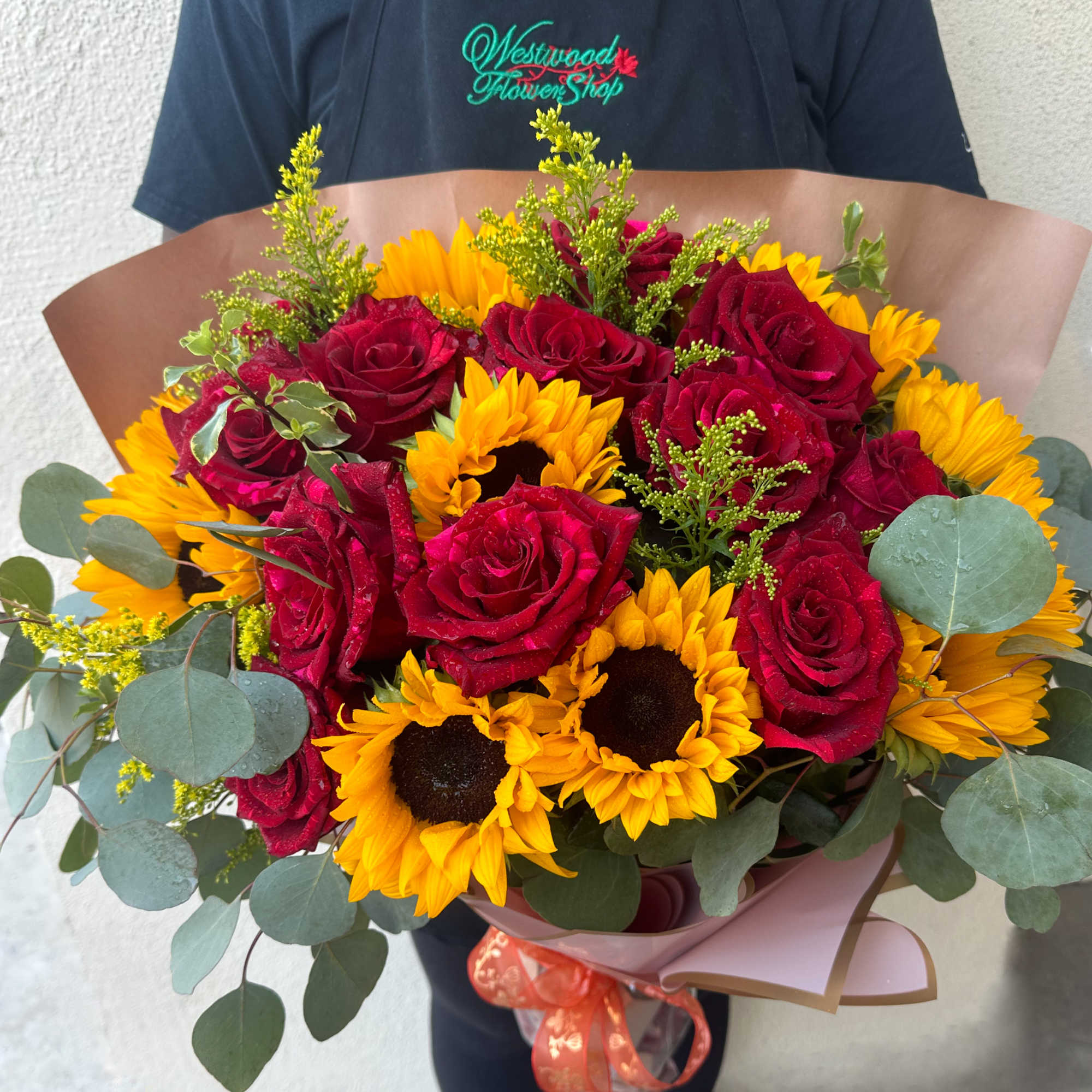 Bouquet of red roses and yellow sunflowers wrapped in pink paper