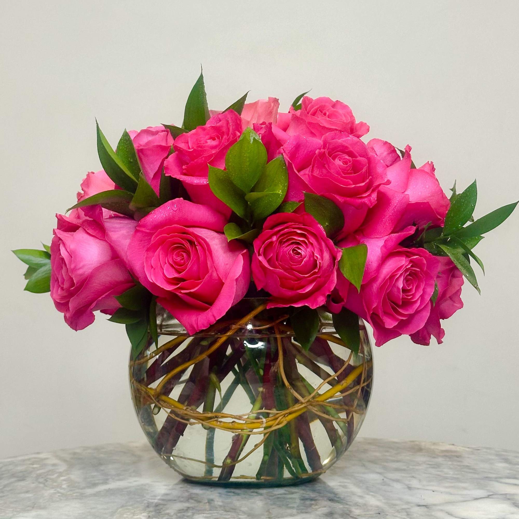 Pink roses arranged in a clear glass bowl vase