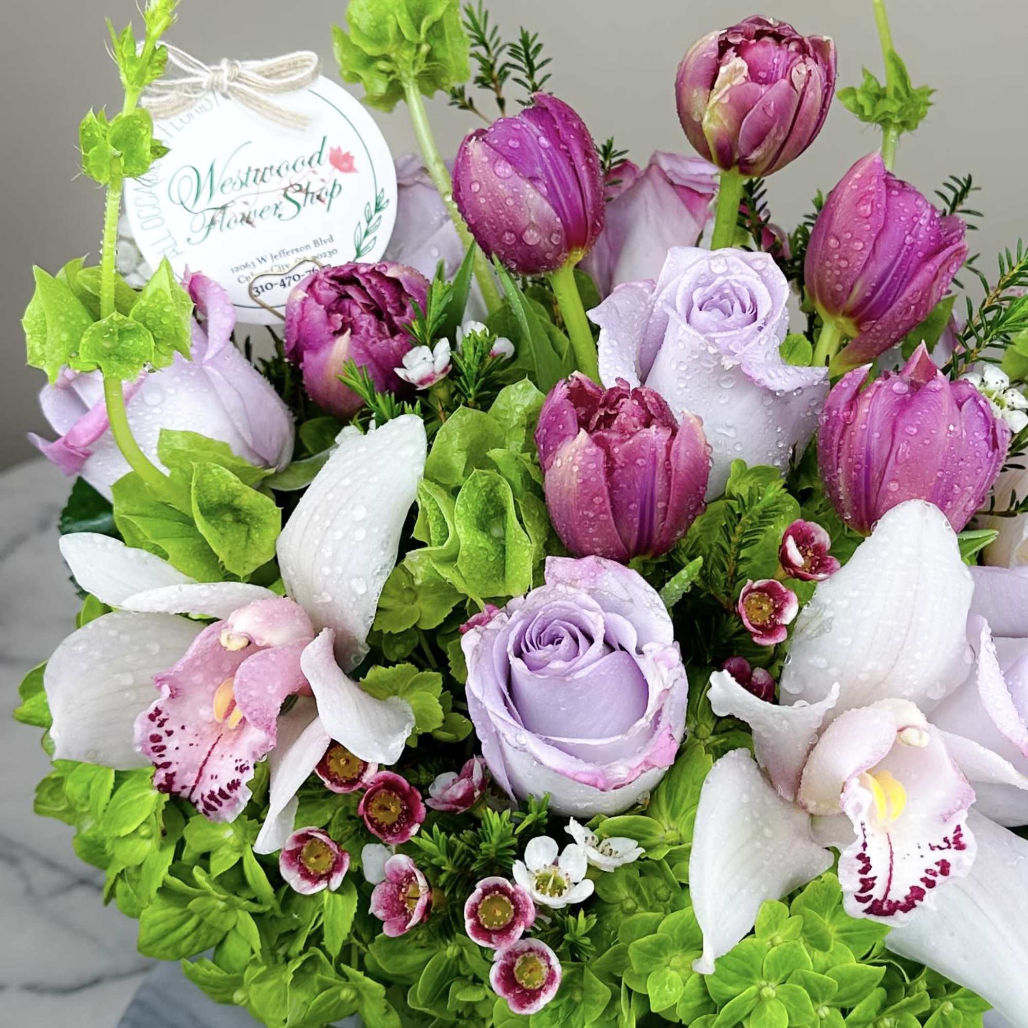 Lavender roses, pink tulips, and white orchids in a compact bouquet