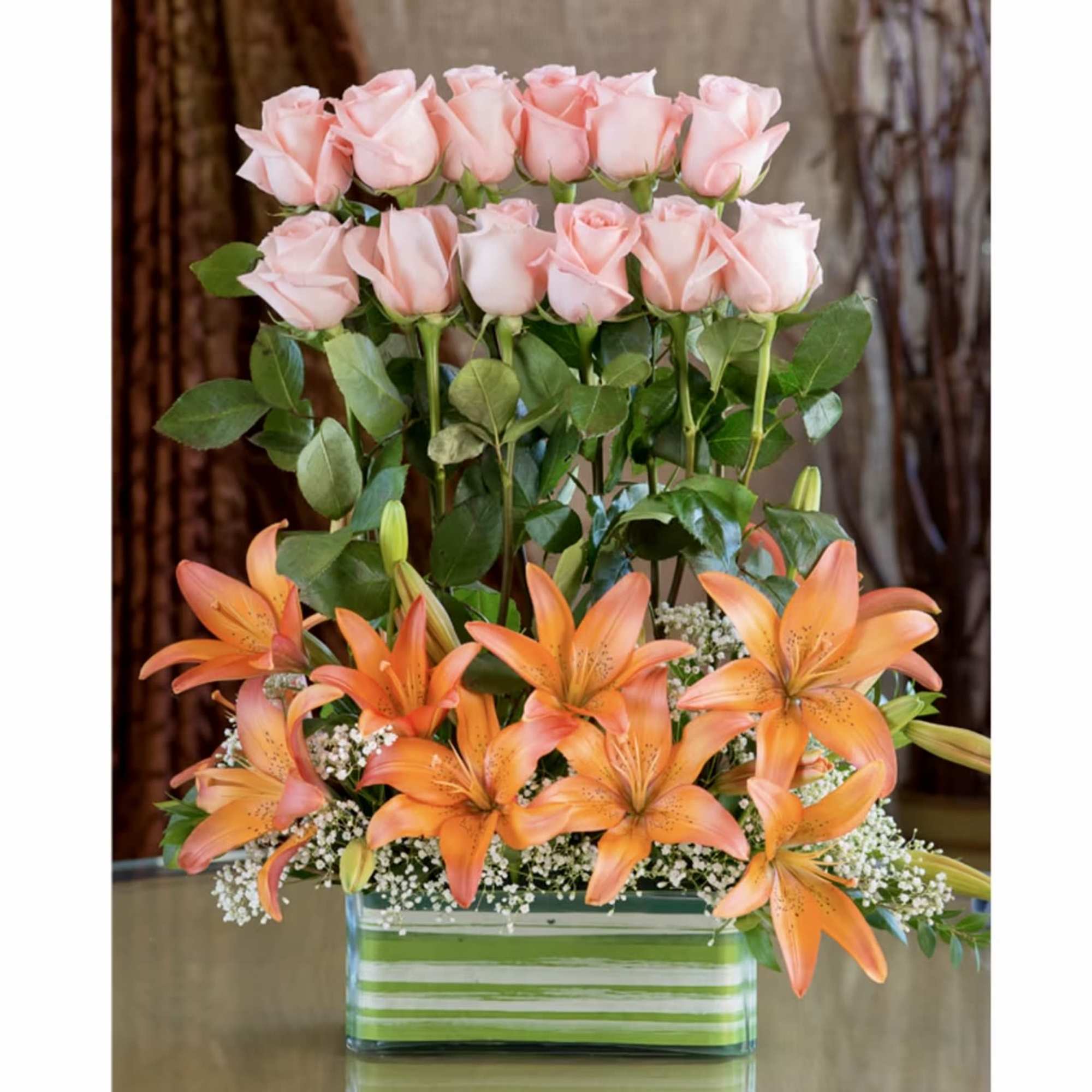 Pink roses and orange lilies in a striped glass vase