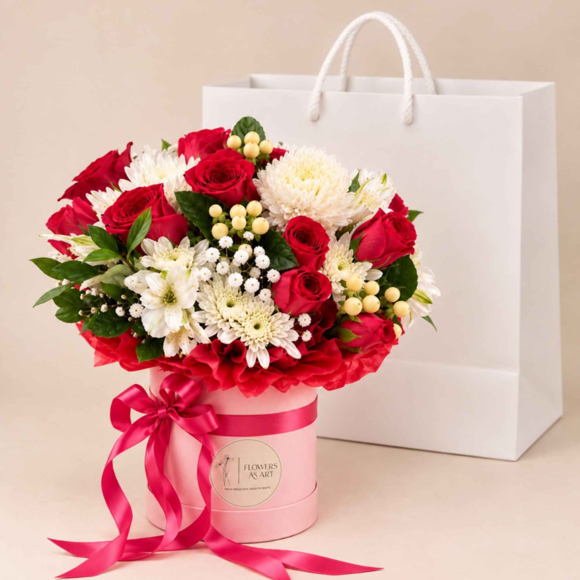 Red roses and white chrysanthemums in a pink hatbox with a ribbon bow