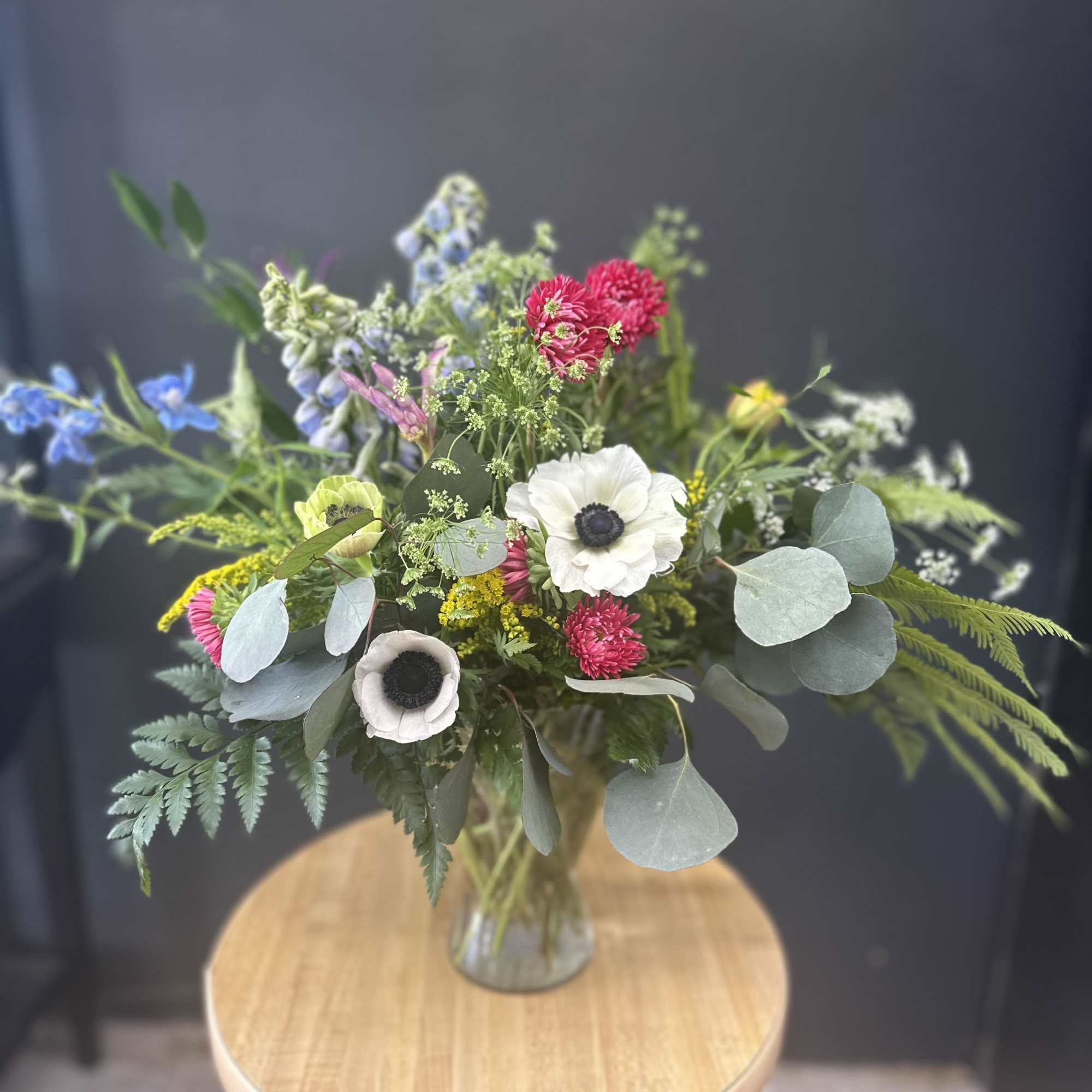 Mixed bouquet in a glass vase with white, pink, blue, and yellow flowers