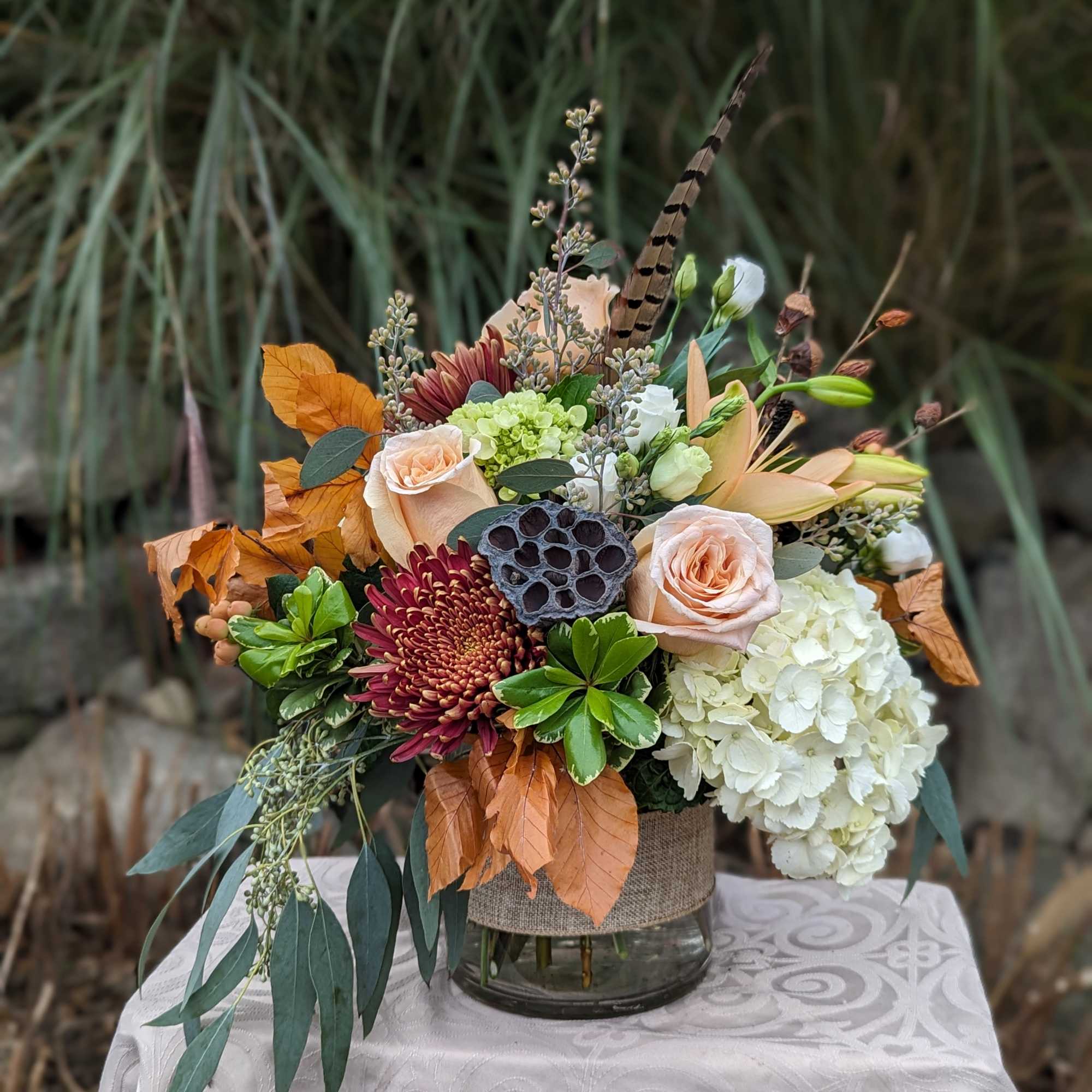 Autumn floral arrangement with roses, hydrangea, and chrysanthemums in a glass vase
