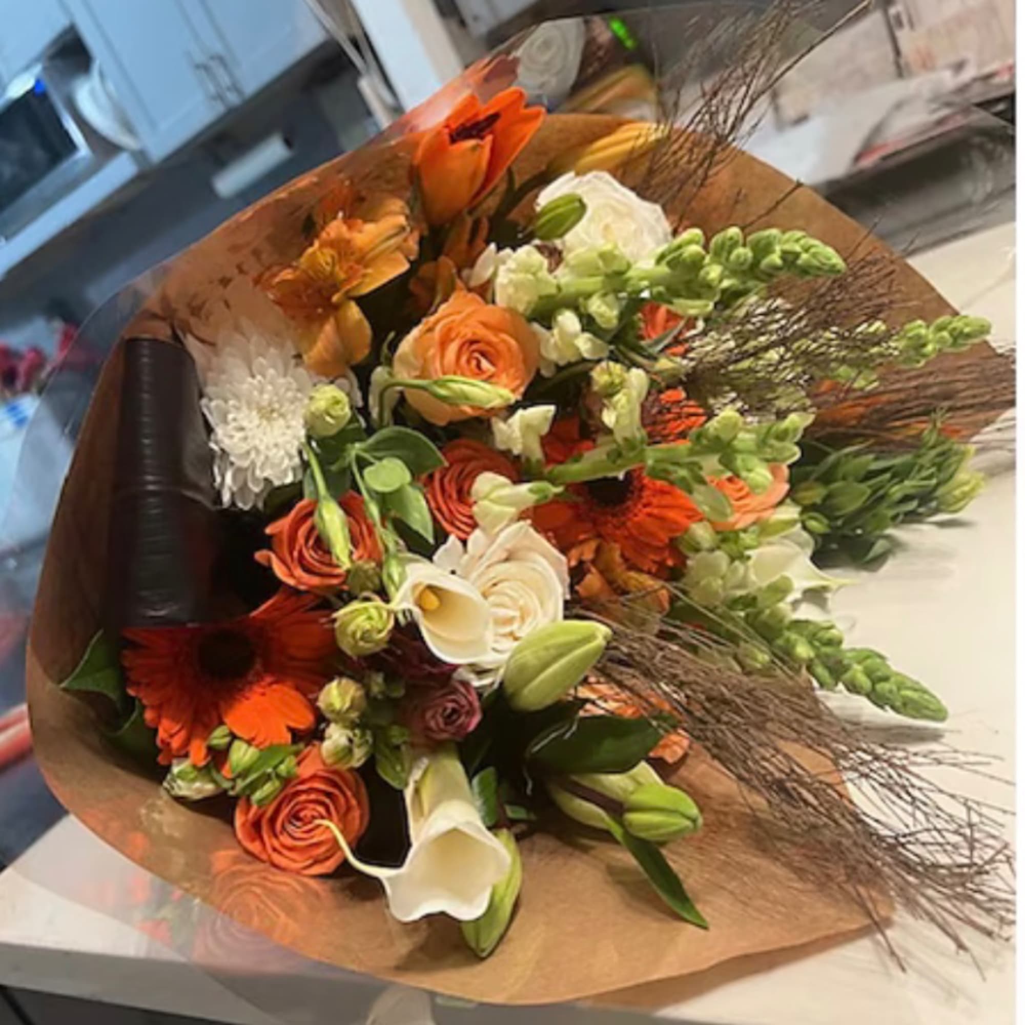 Bouquet of orange and white flowers wrapped in brown paper