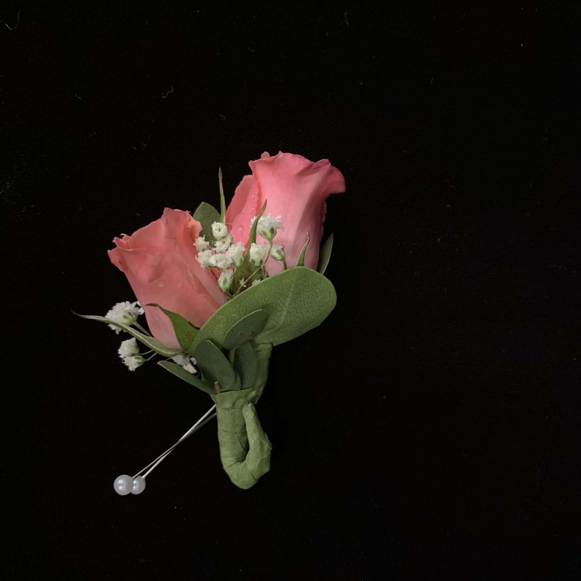 Two pink rose boutonnieres with small white filler flowers
