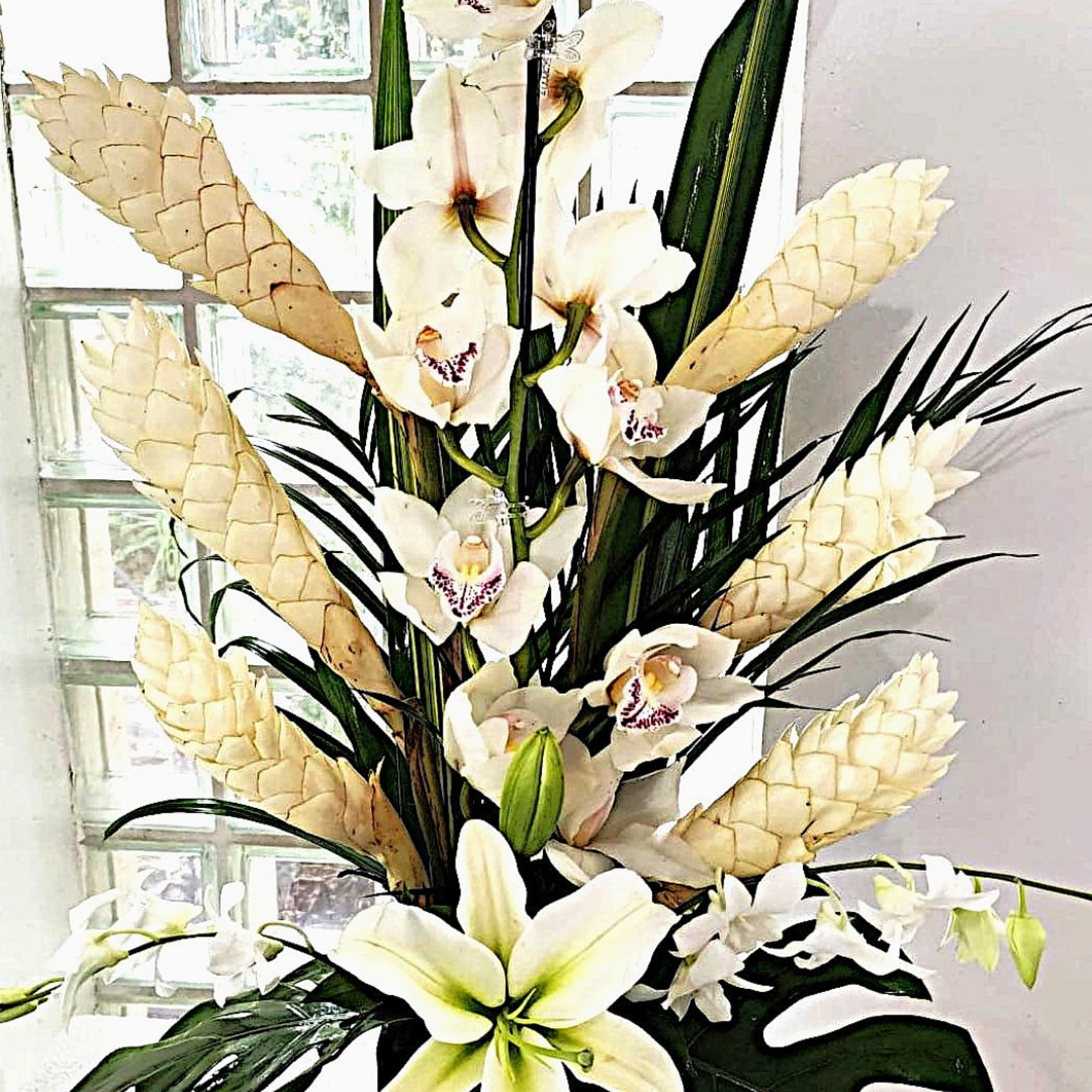 Tall arrangement of white orchids and lilies with pale cone accents