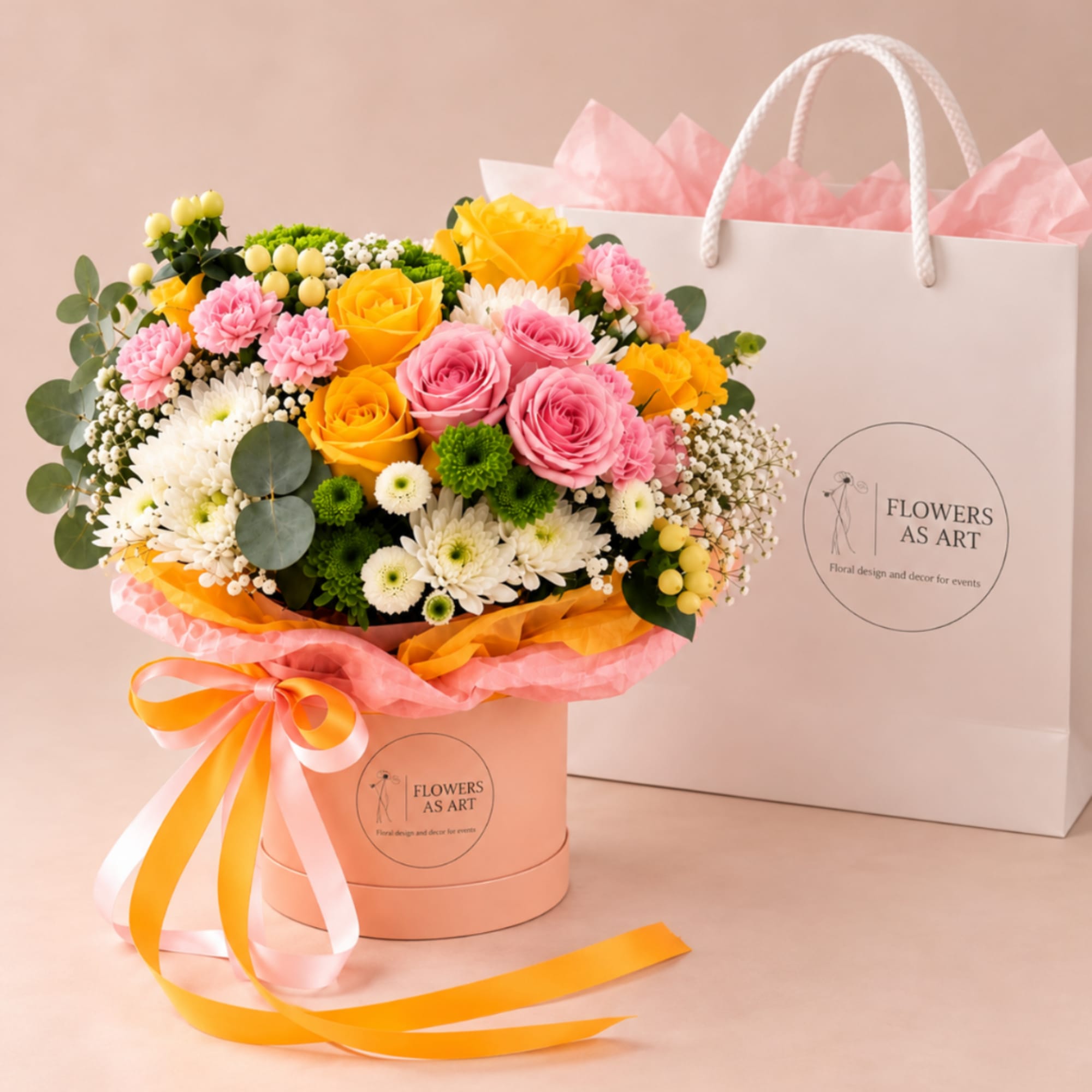 Bouquet of pink and yellow roses in a peach hatbox with ribbon