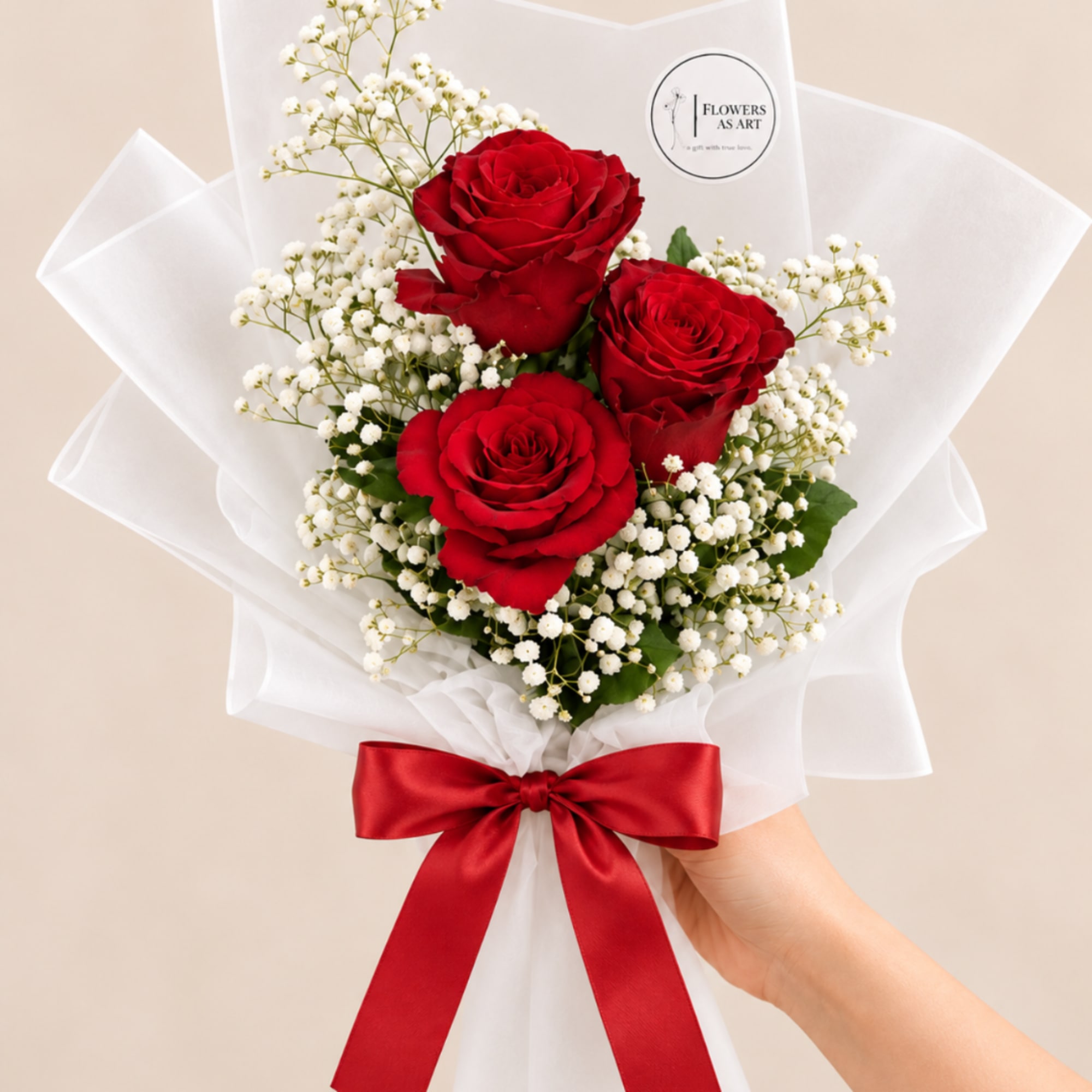 Bouquet of red roses and white baby's breath wrapped in white paper with a red ribbon