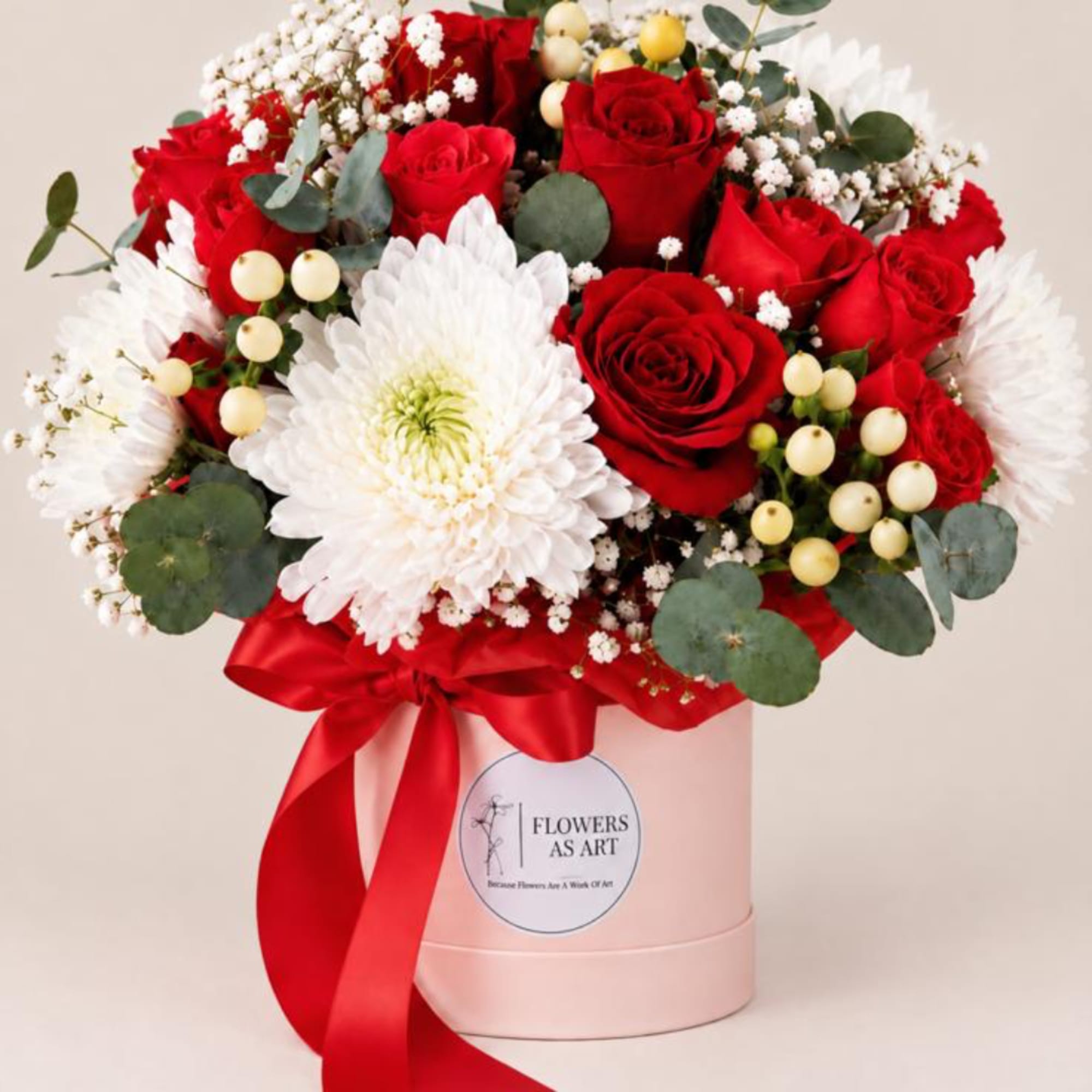 Red roses and white chrysanthemums in a pink hat box with a red ribbon