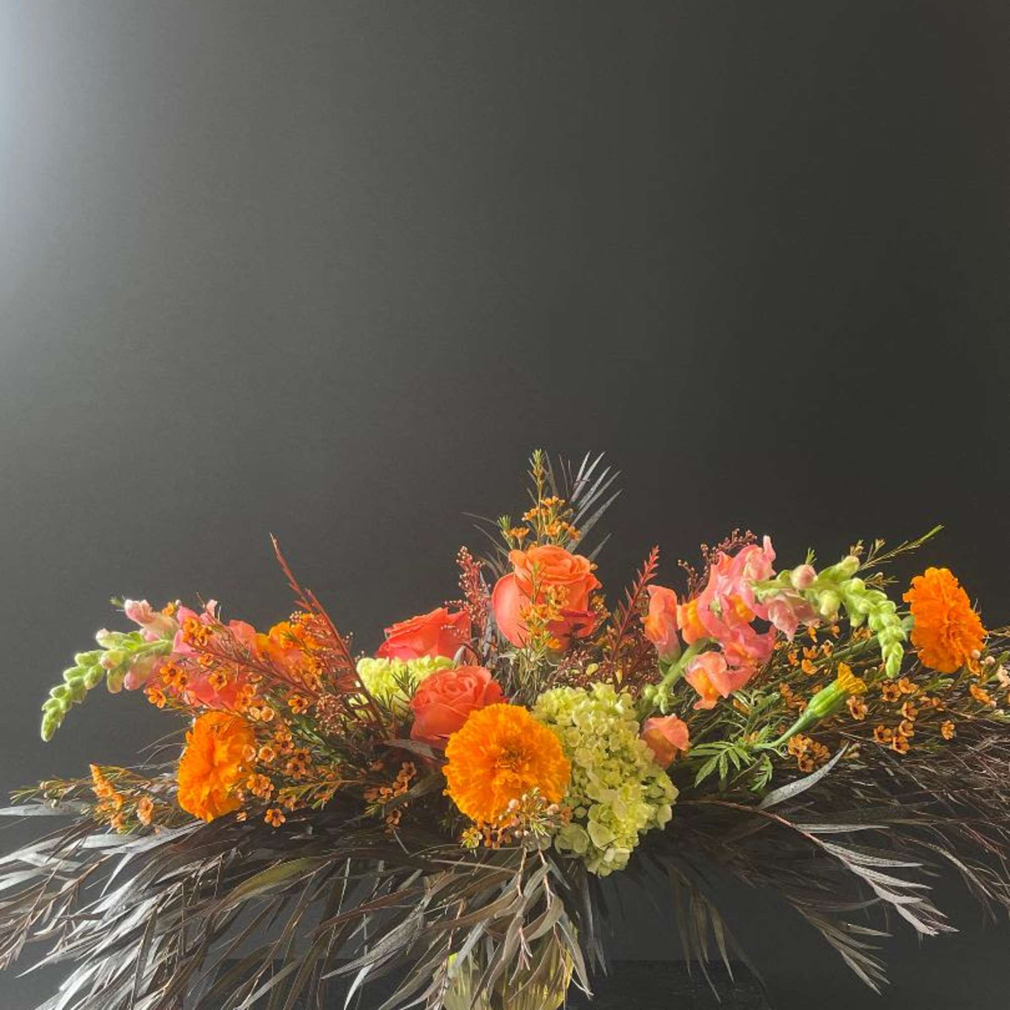 Orange and pink floral arrangement in a gold vase