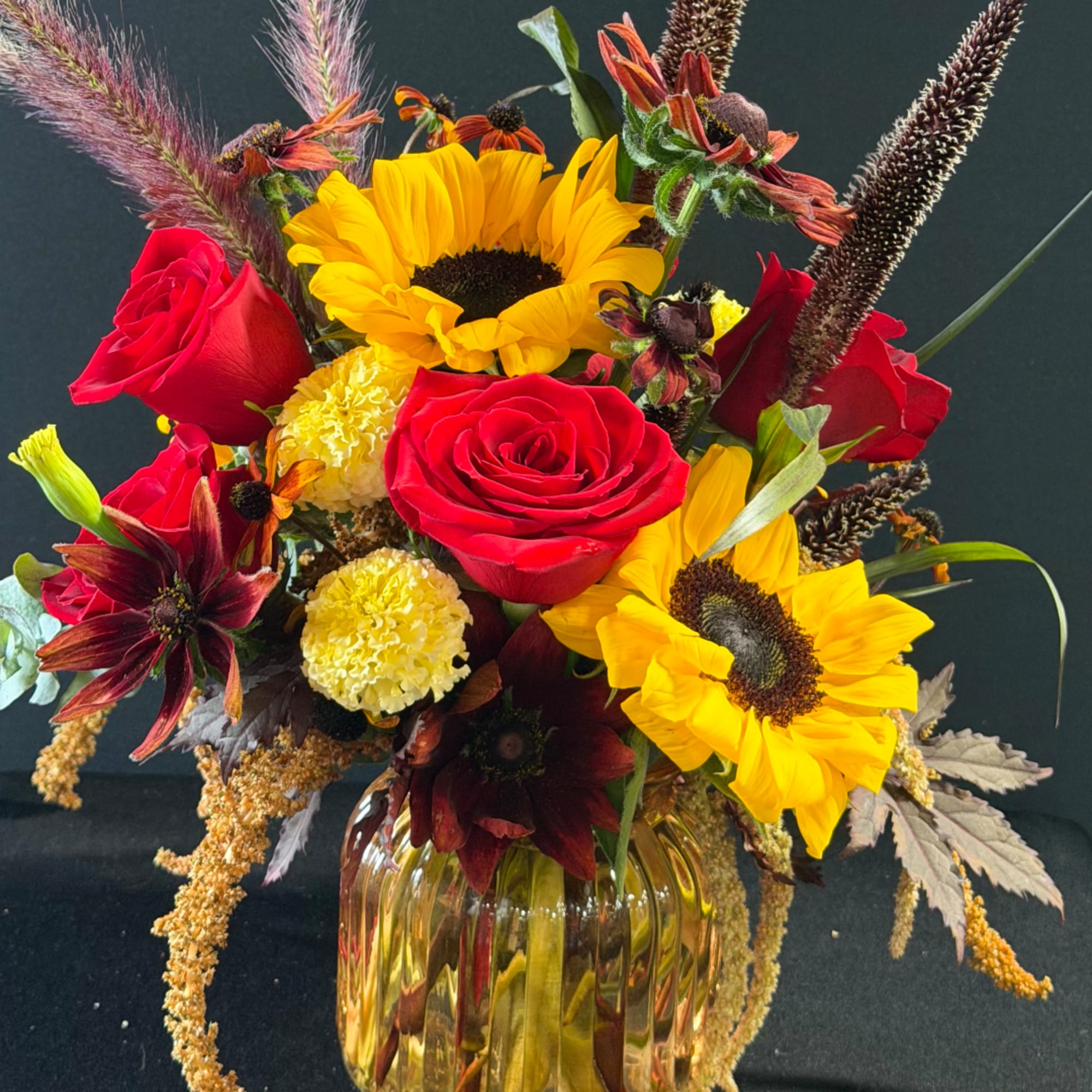 Bouquet of red roses and yellow sunflowers in a glass vase