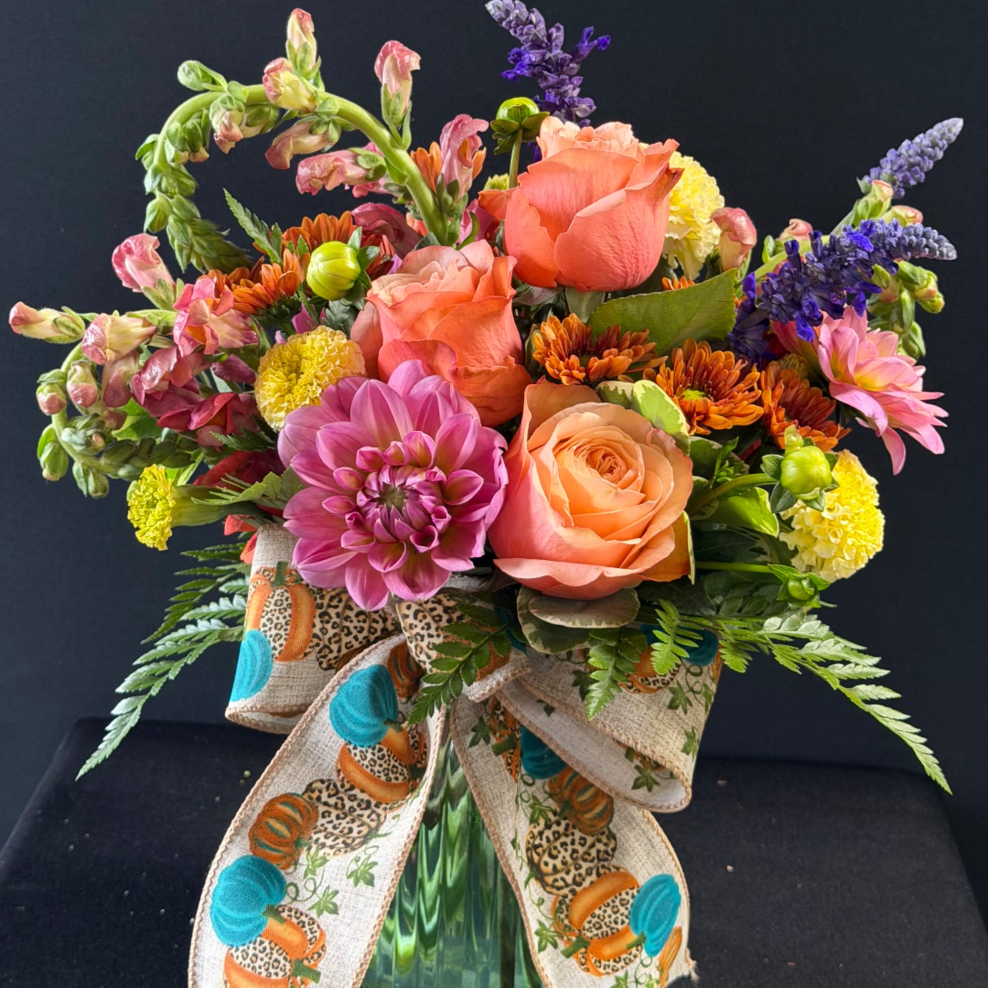 Colorful mixed bouquet in a glass vase with a patterned ribbon bow