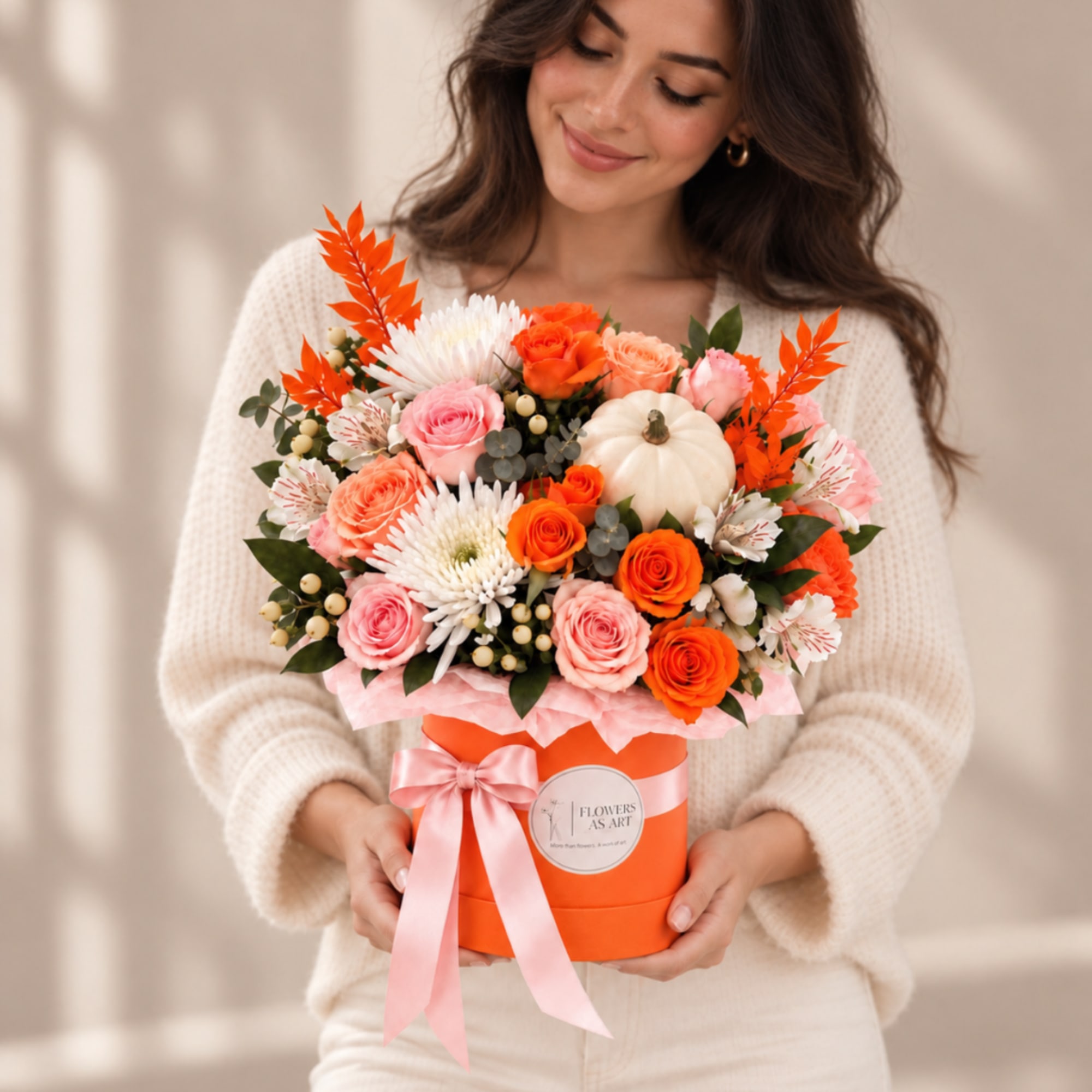 Woman holding a mixed bouquet in an orange hatbox with a pink ribbon