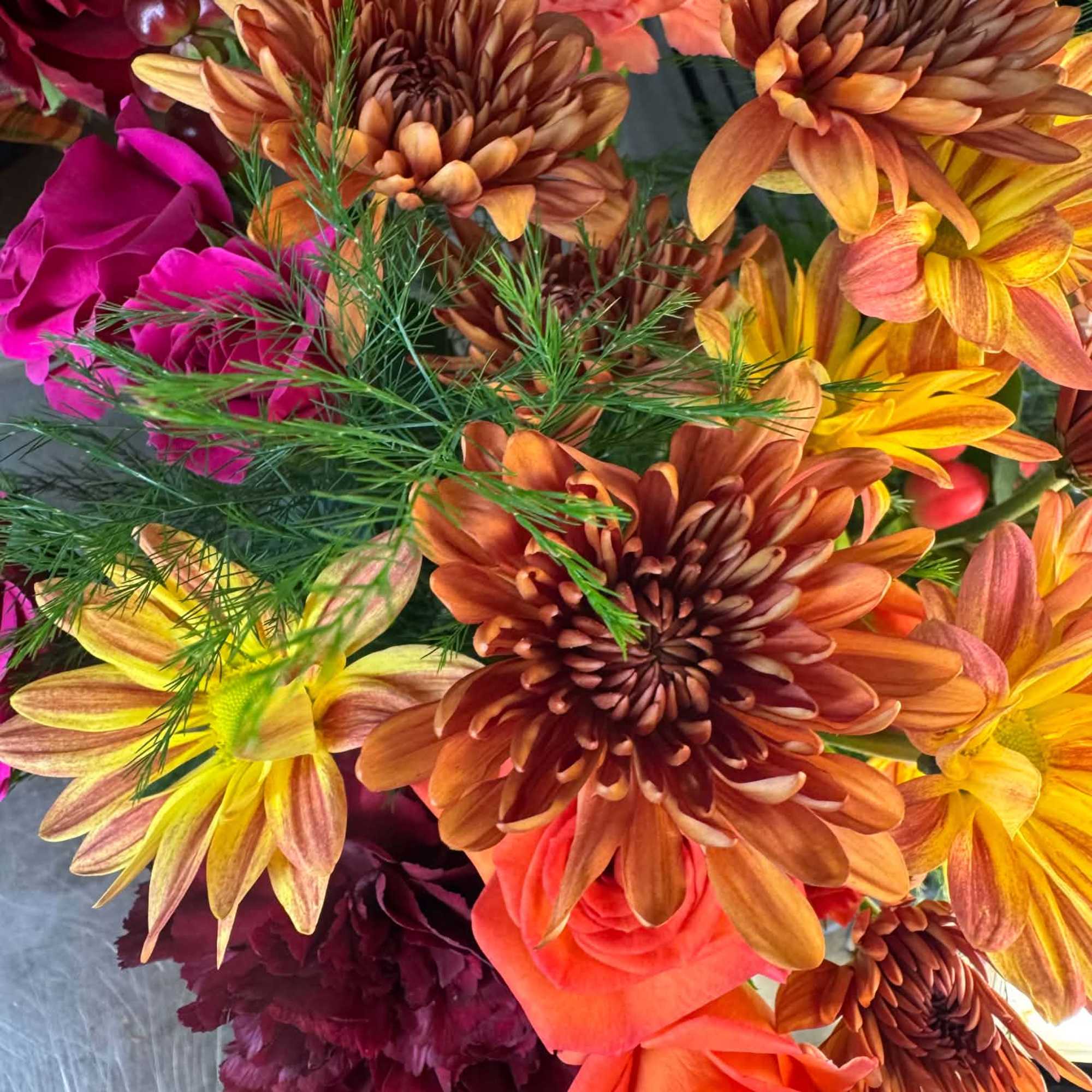 Bouquet of orange, yellow, and pink flowers with burgundy accents
