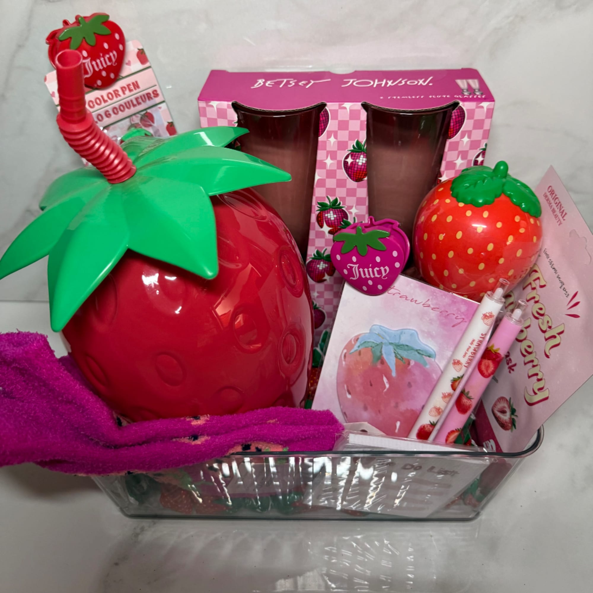 Strawberry-themed gift basket with cups, pens, and packaged accessories