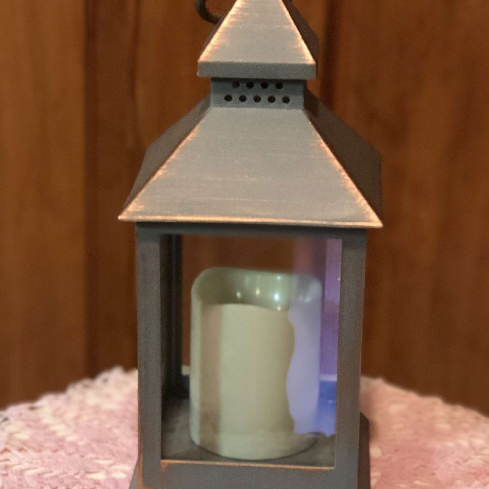 Metal lantern with a candle inside on a pink textured cloth