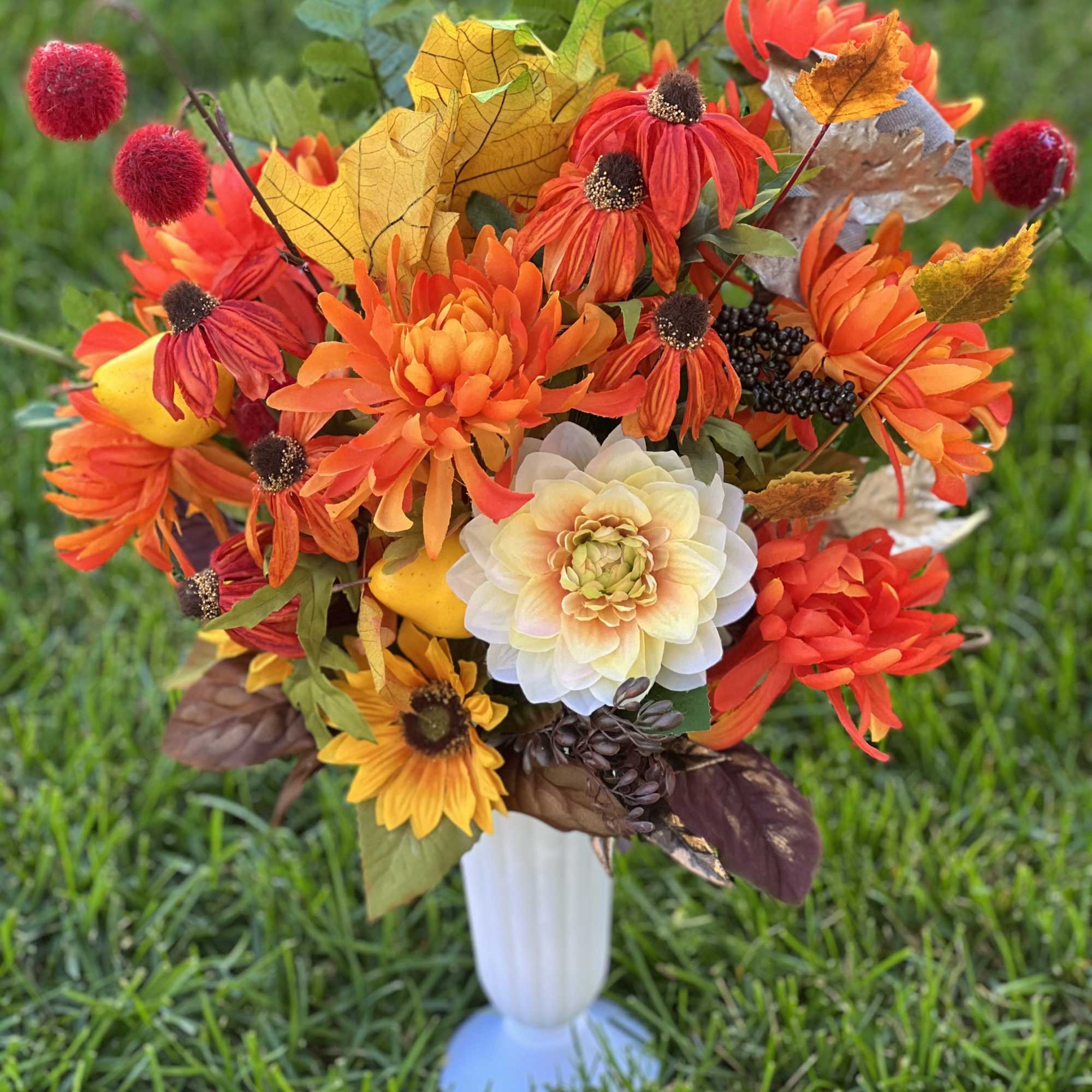 Autumn bouquet of orange and red flowers in a white vase