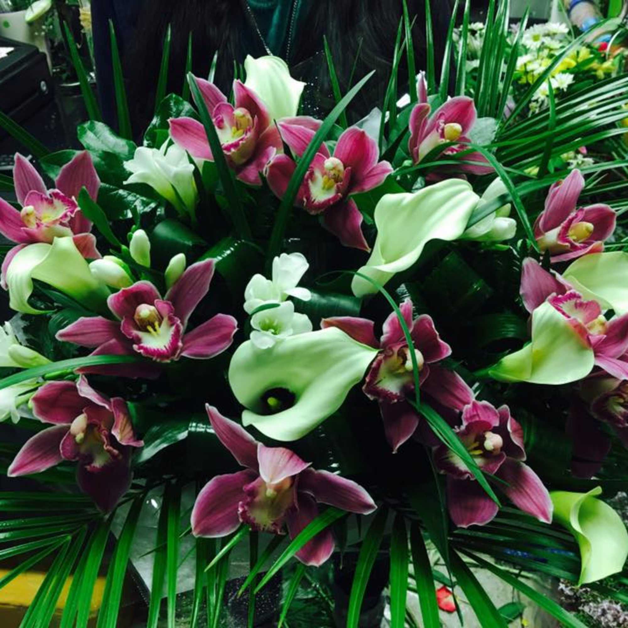 Arrangement of pink orchids and white calla lilies with long palm fronds