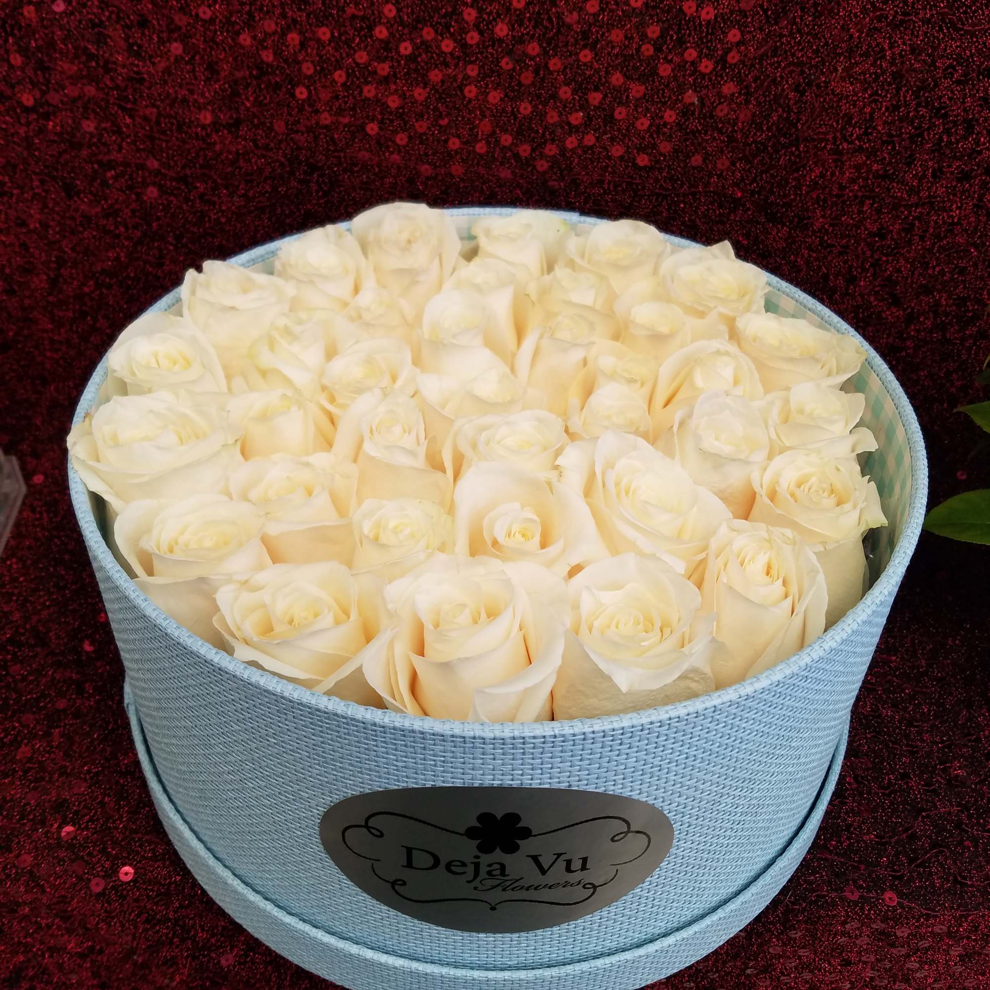 Cream roses arranged in a light blue round box