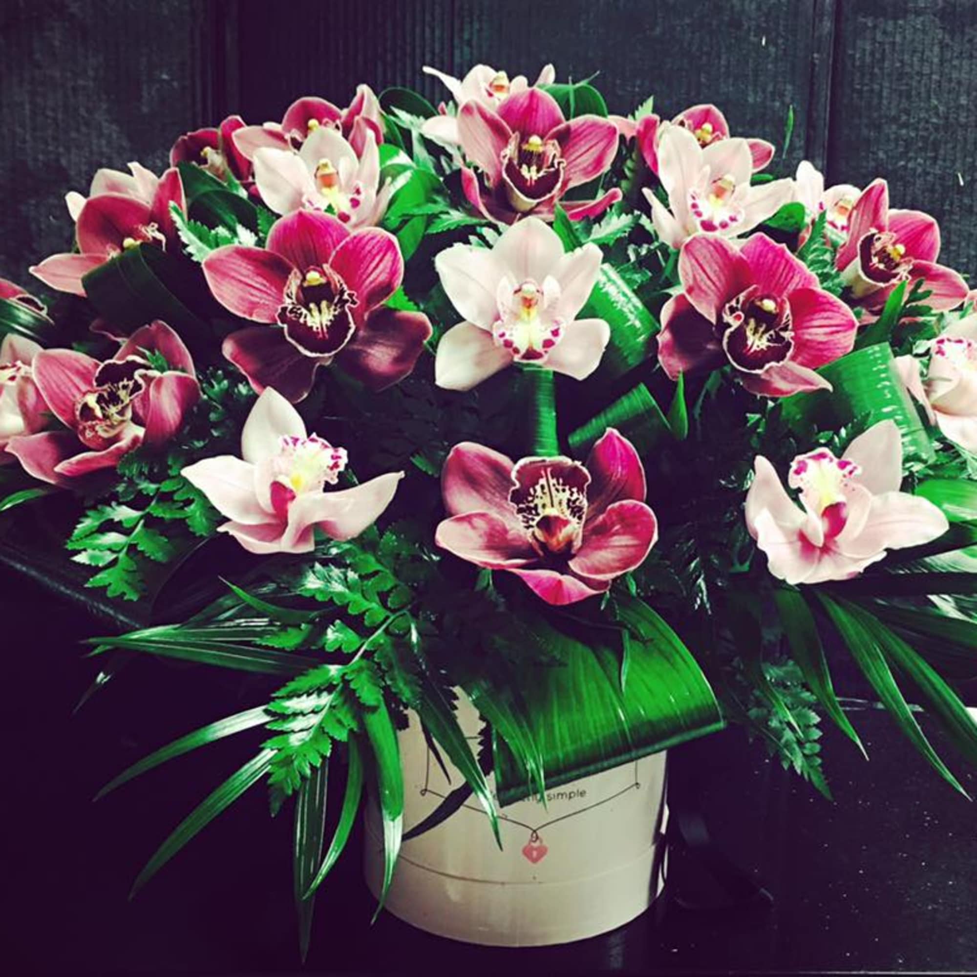 Pink and white orchids arranged in a white container