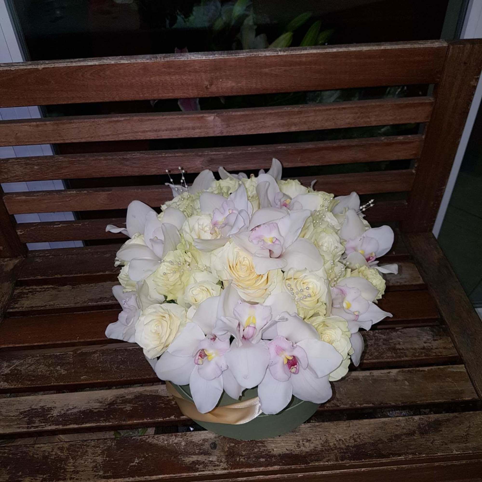 White orchids and cream roses arranged in a round box