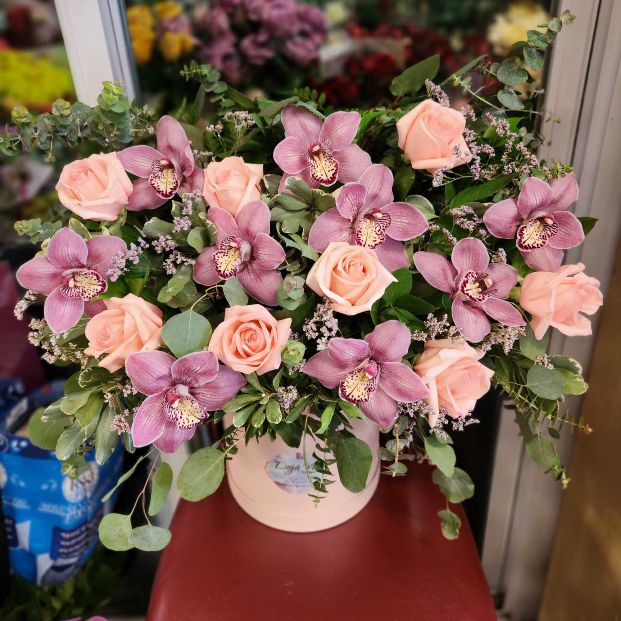 Pink roses and orchids arranged in a pale vase