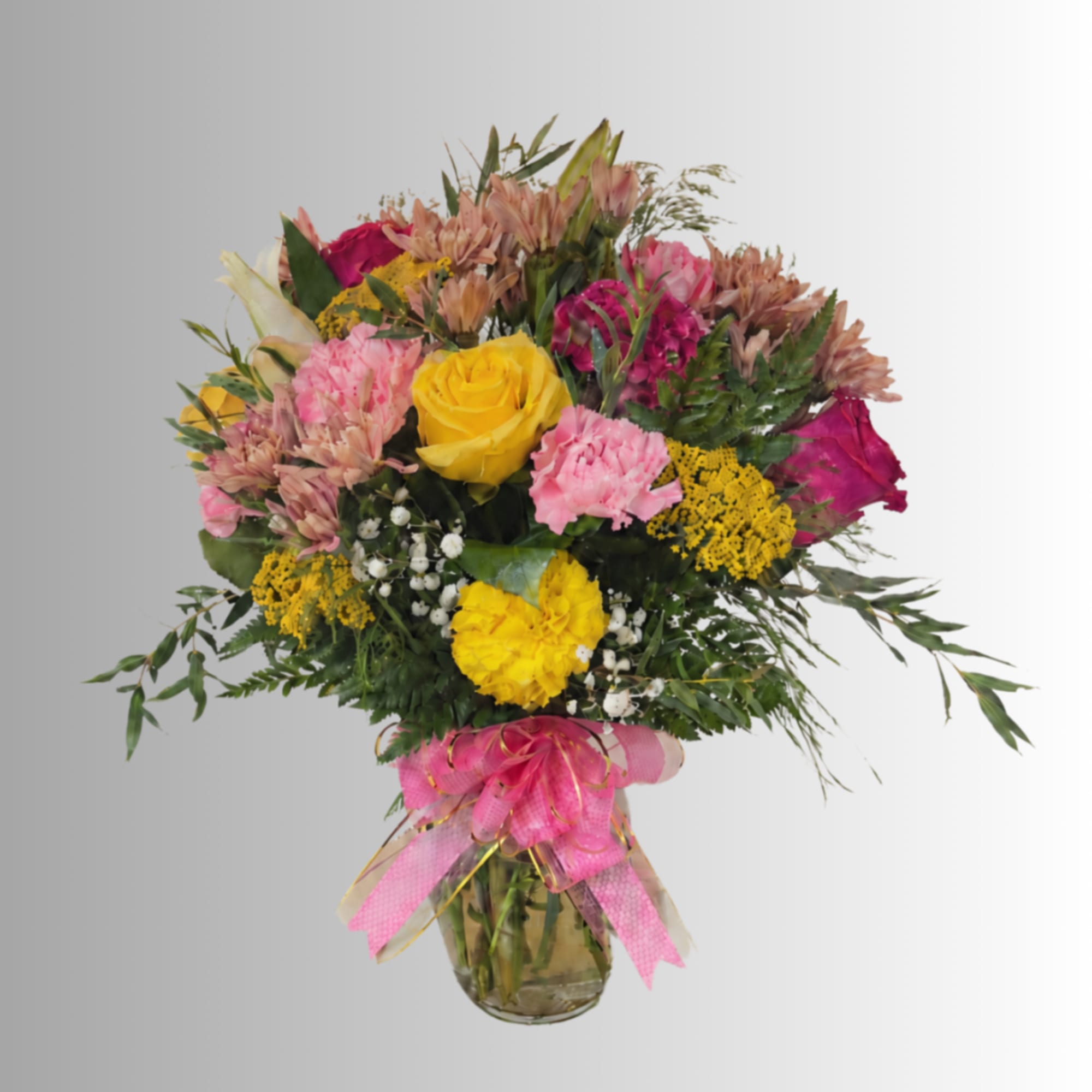 Mixed bouquet of roses, carnations, and daisies in a glass vase with a pink ribbon