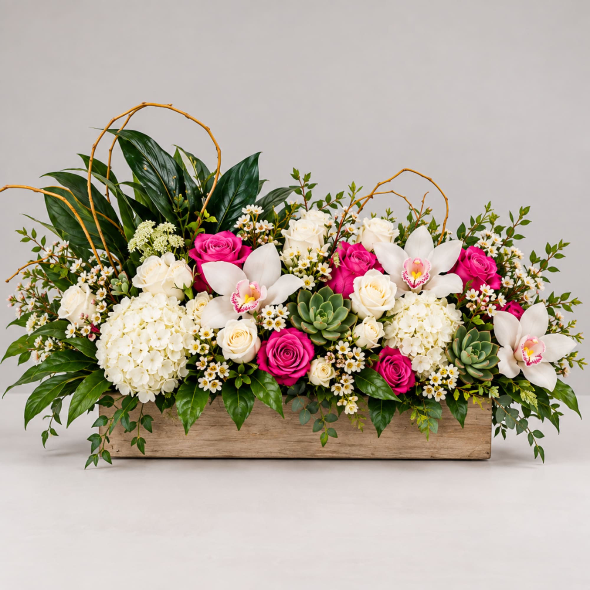 Long floral arrangement in a wooden box with white orchids, roses, and pink roses