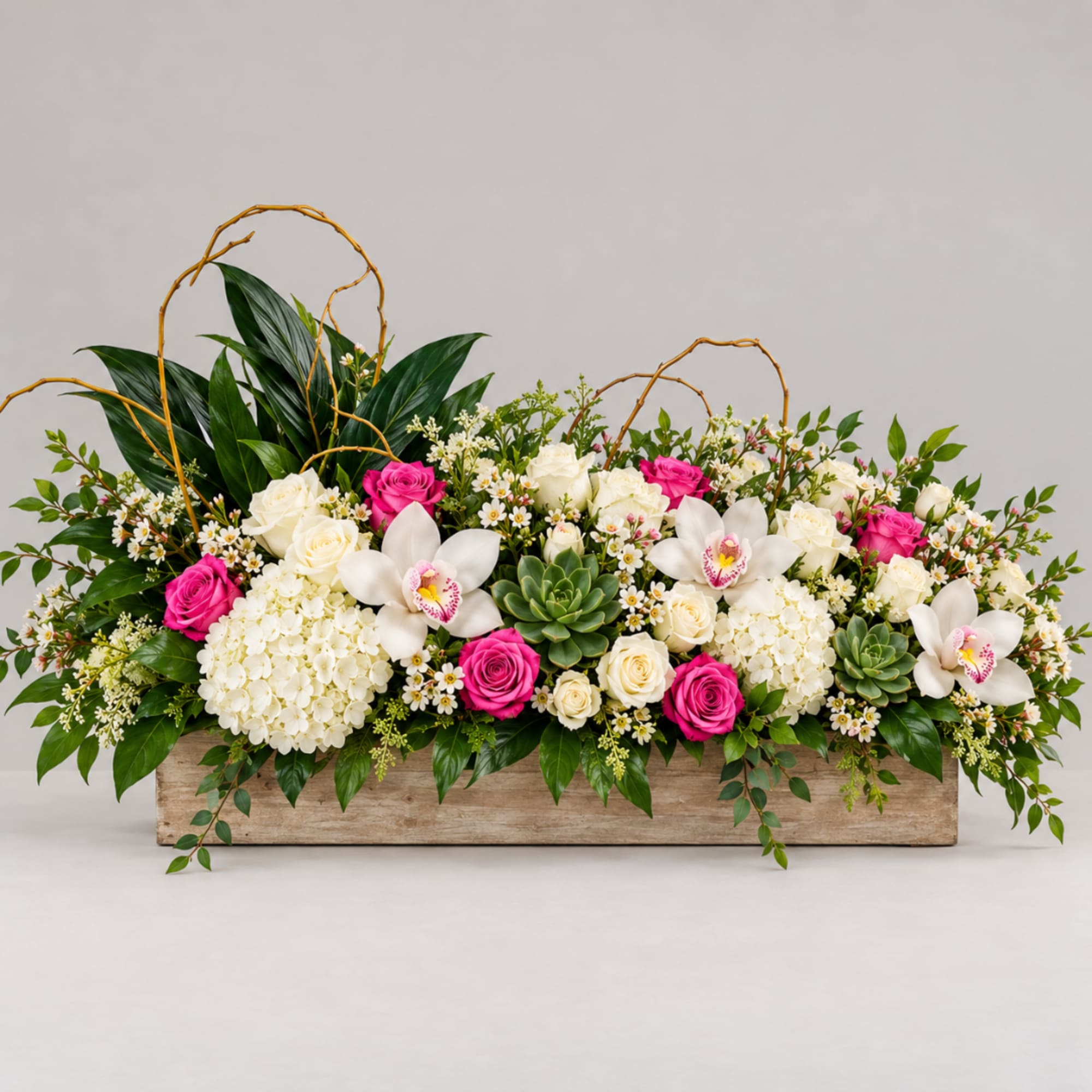 Long floral arrangement with pink and white roses in a wooden box