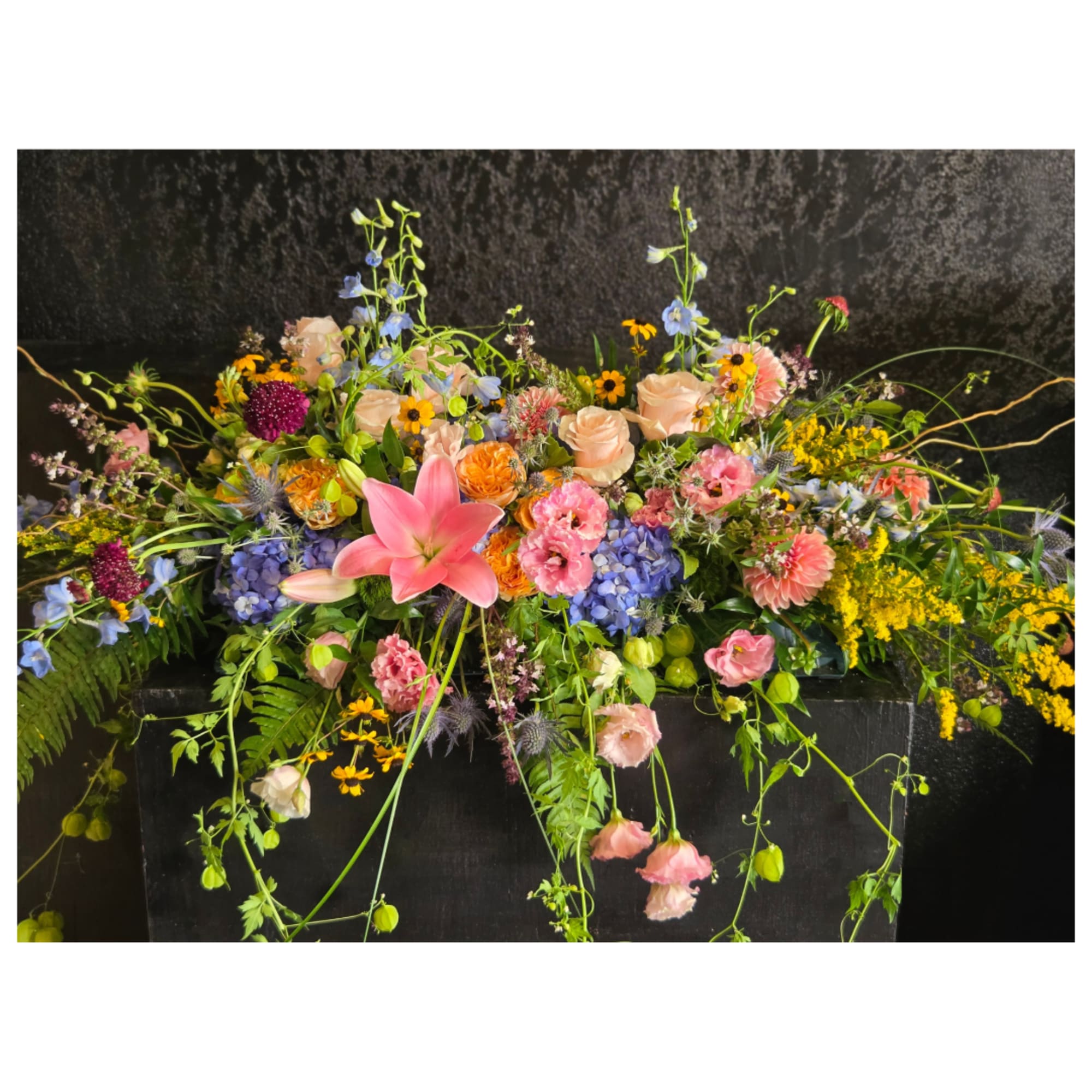 Large mixed floral arrangement with pink lilies, roses, and blue hydrangeas