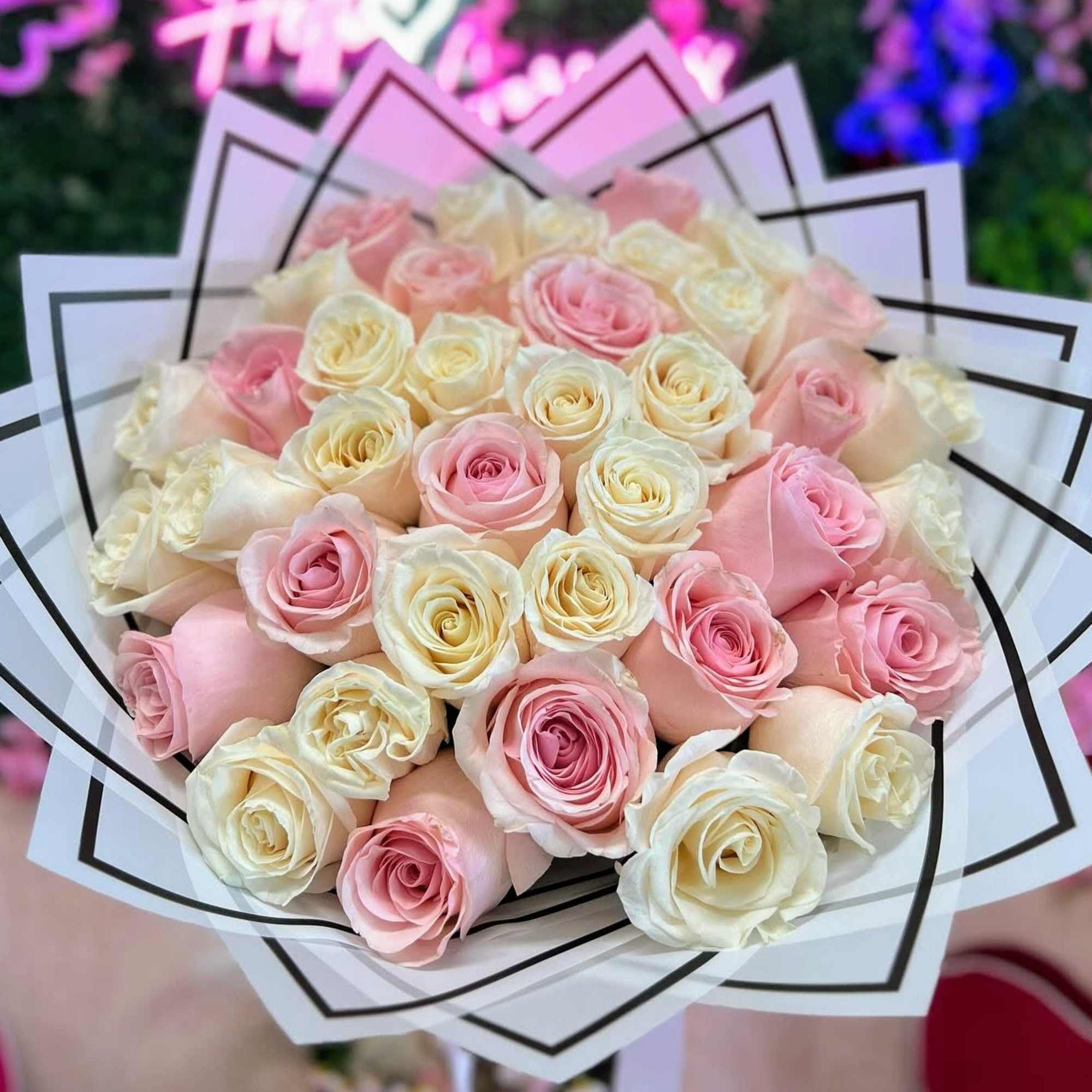 Bouquet of cream and light pink roses wrapped in layered white paper.