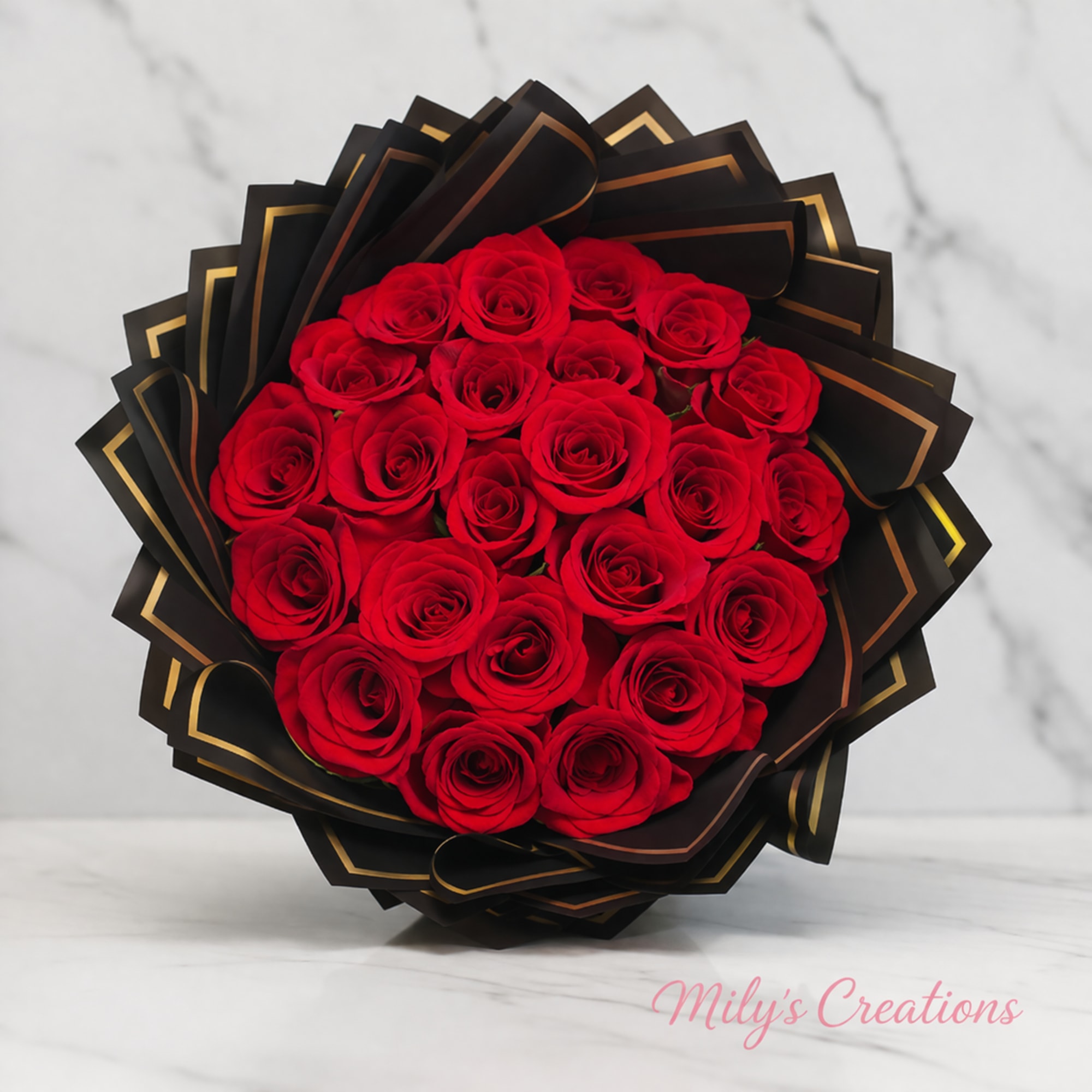 Round bouquet of red roses wrapped in black and gold paper on a marble surface