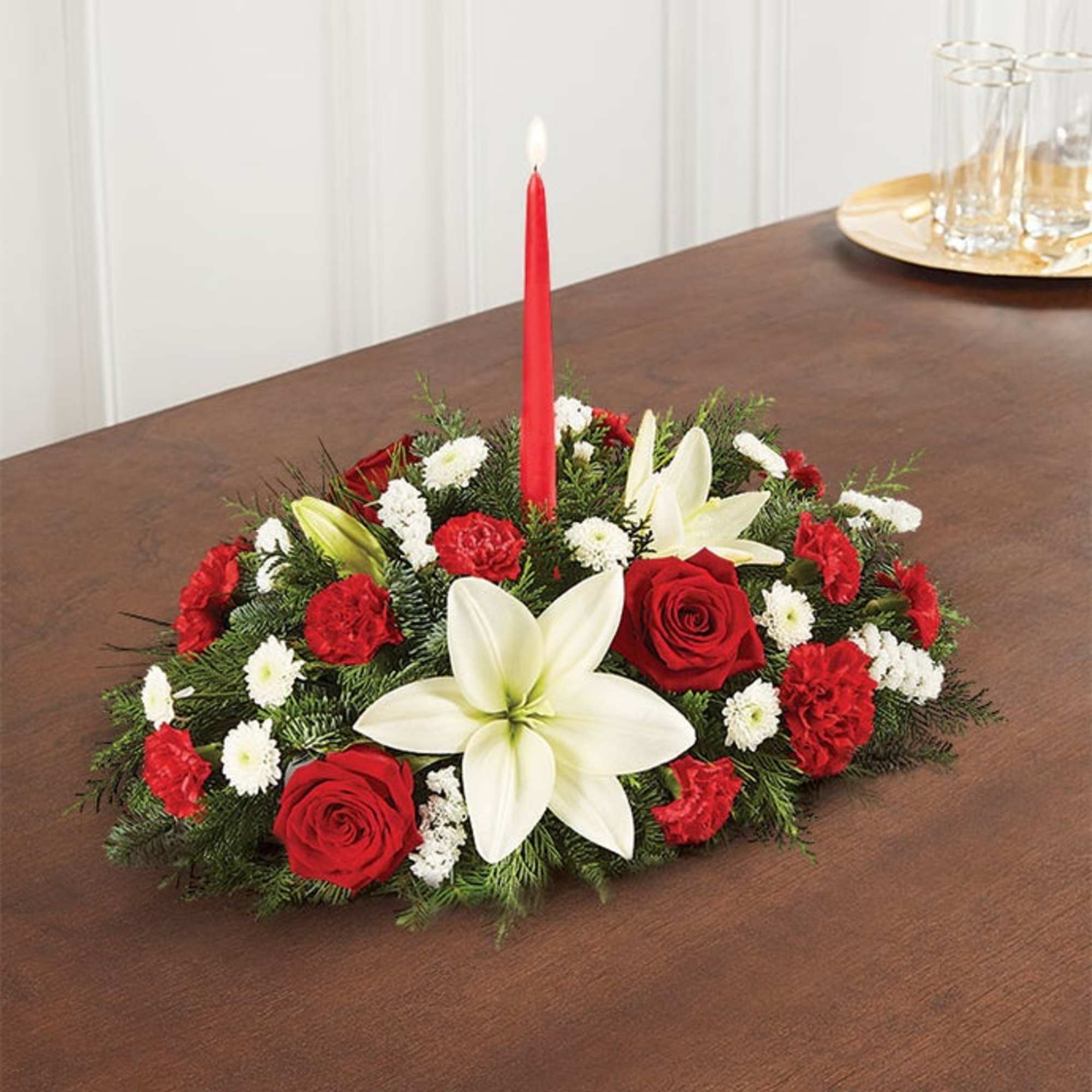 Low floral centerpiece with red roses, white lilies, and a red taper candle