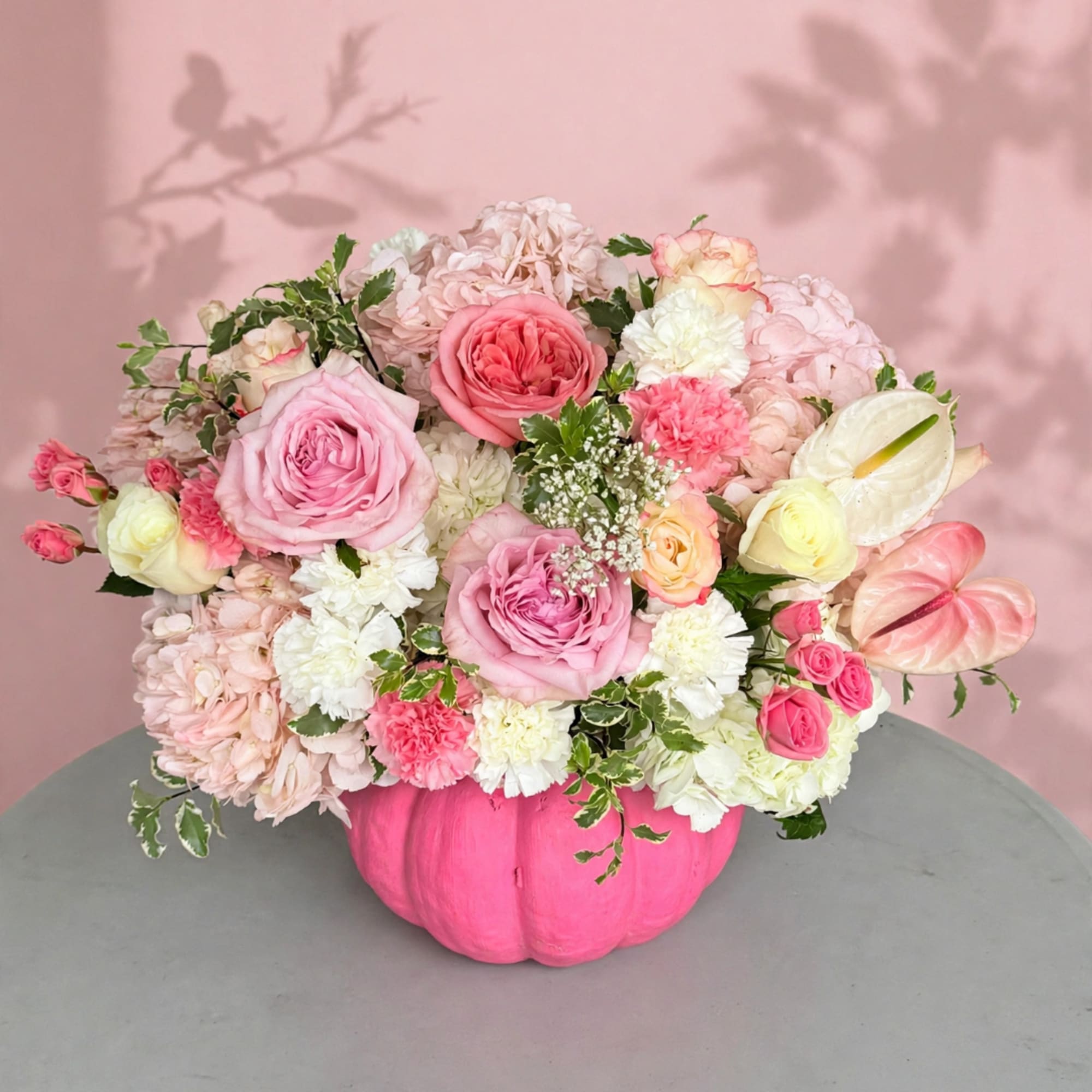 Pink and white floral arrangement in a bright pink pumpkin vase