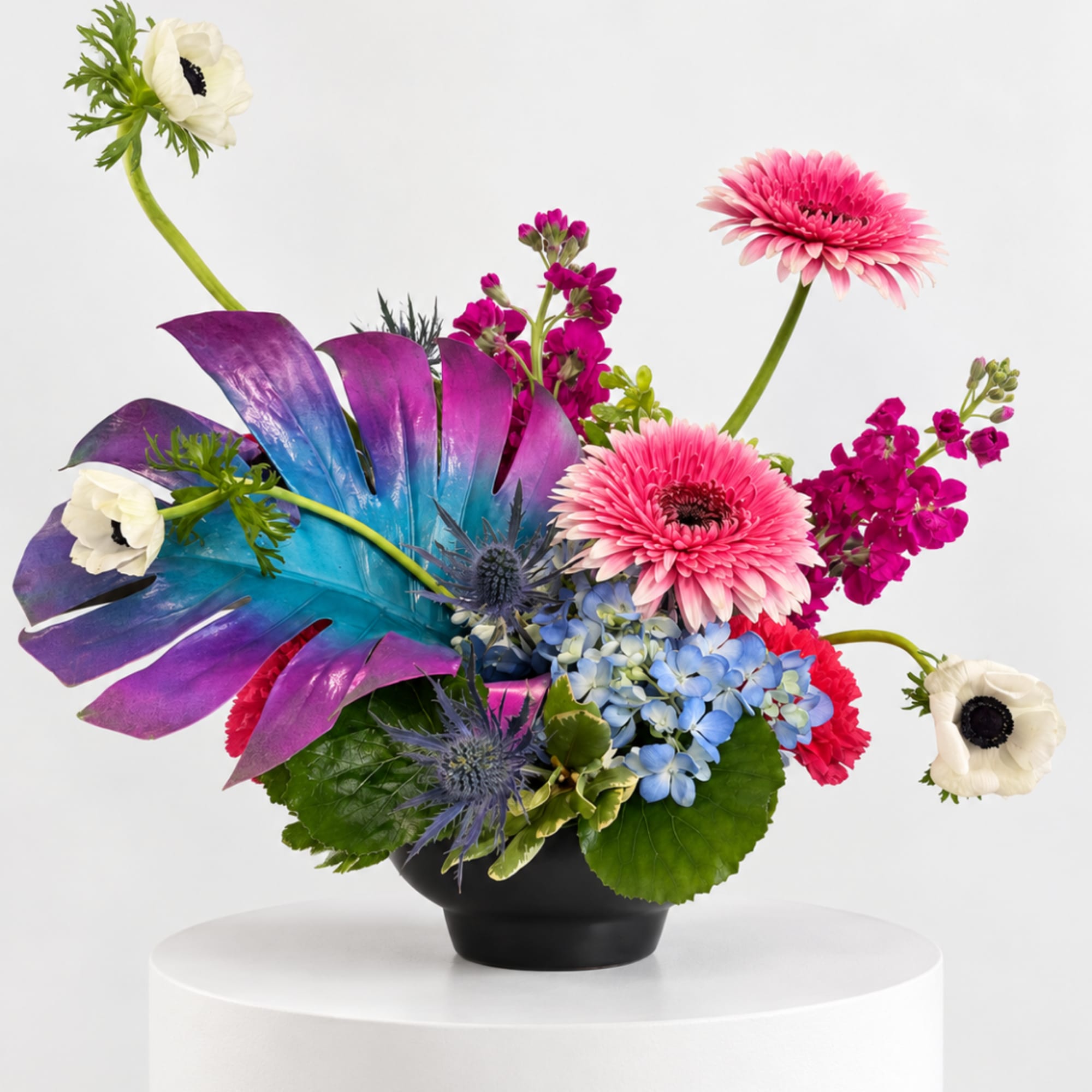 Colorful floral arrangement in a black bowl with pink gerberas and white anemones